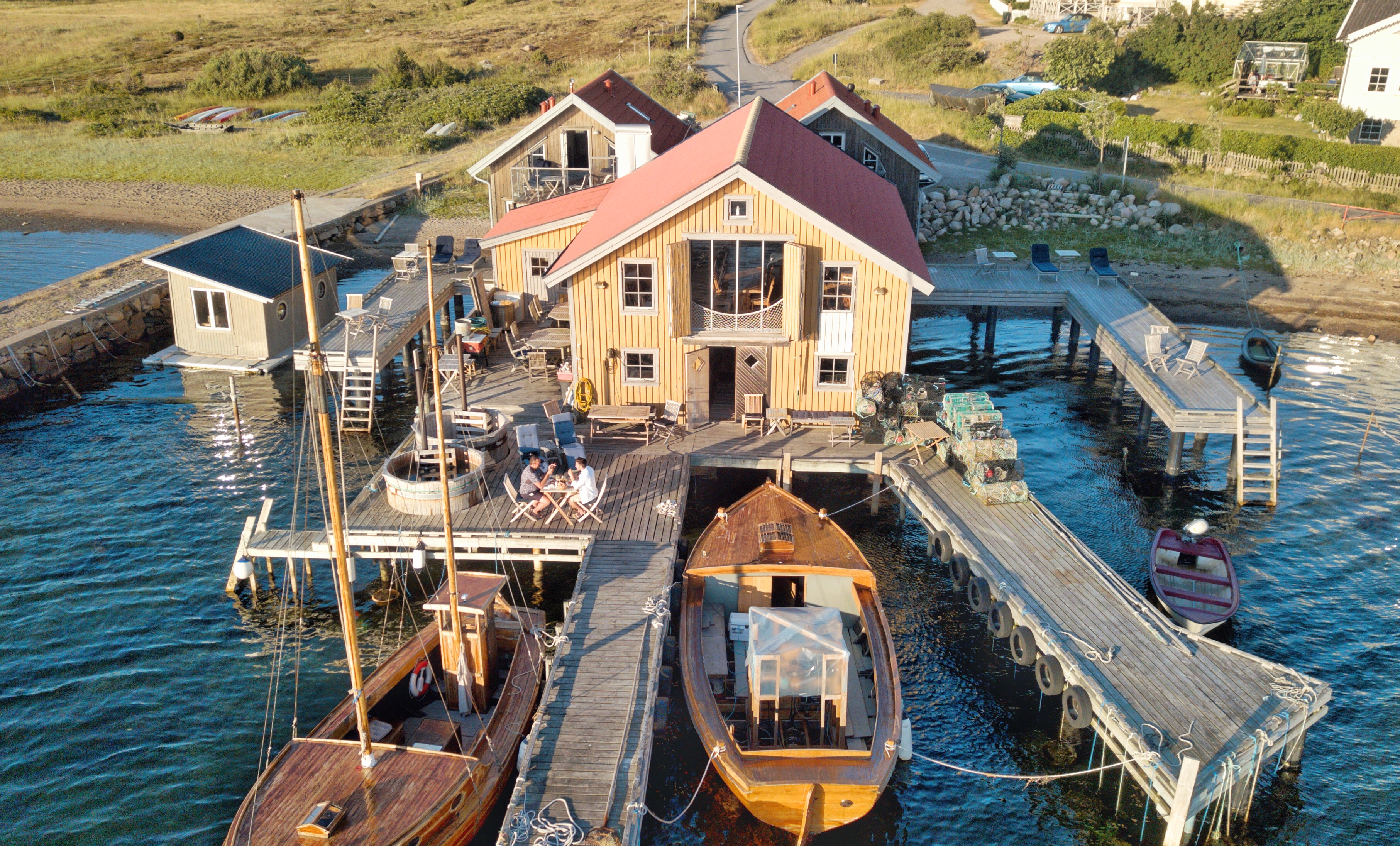 Everts Sjöbod in Grebbestad, een hotel in een boothuis aan het water met houten steigers, boten en zitjes in de open lucht aan zee.