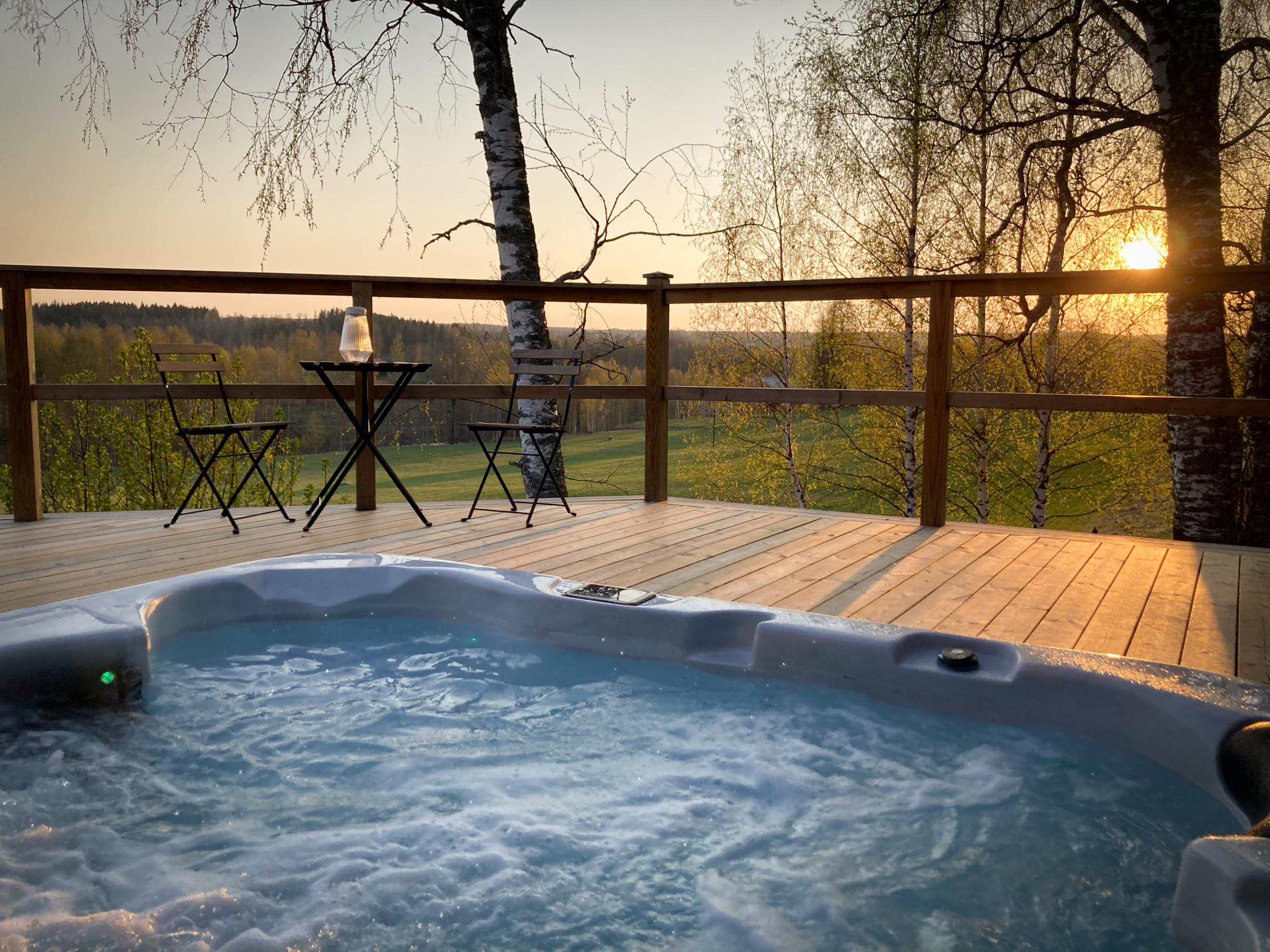Blick von einem Whirlpool auf eine Terrasse mit Blick auf die Wiesen und Wälder.