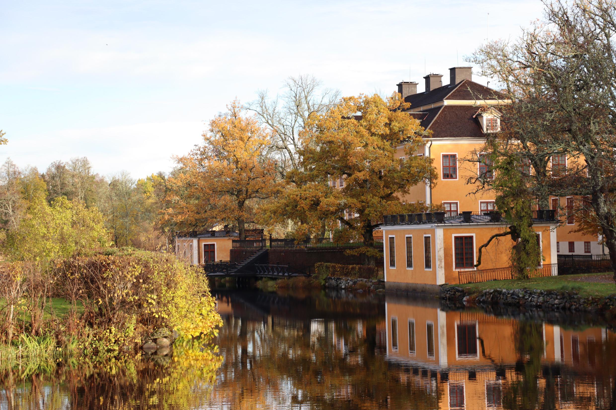La demeure de Lövstabruk avec sa façade orange et ses contours blancs au bord de l'eau.
