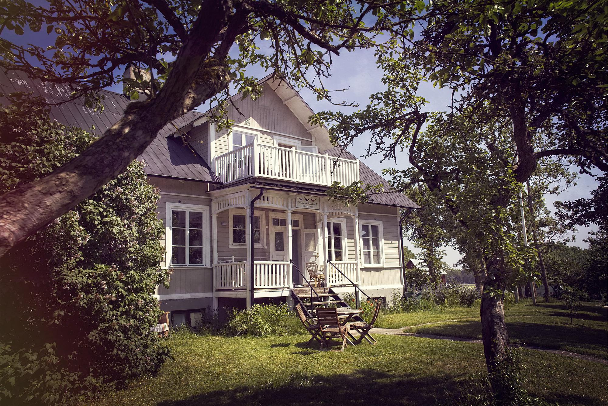 Een wit houten huis omgeven door groen.