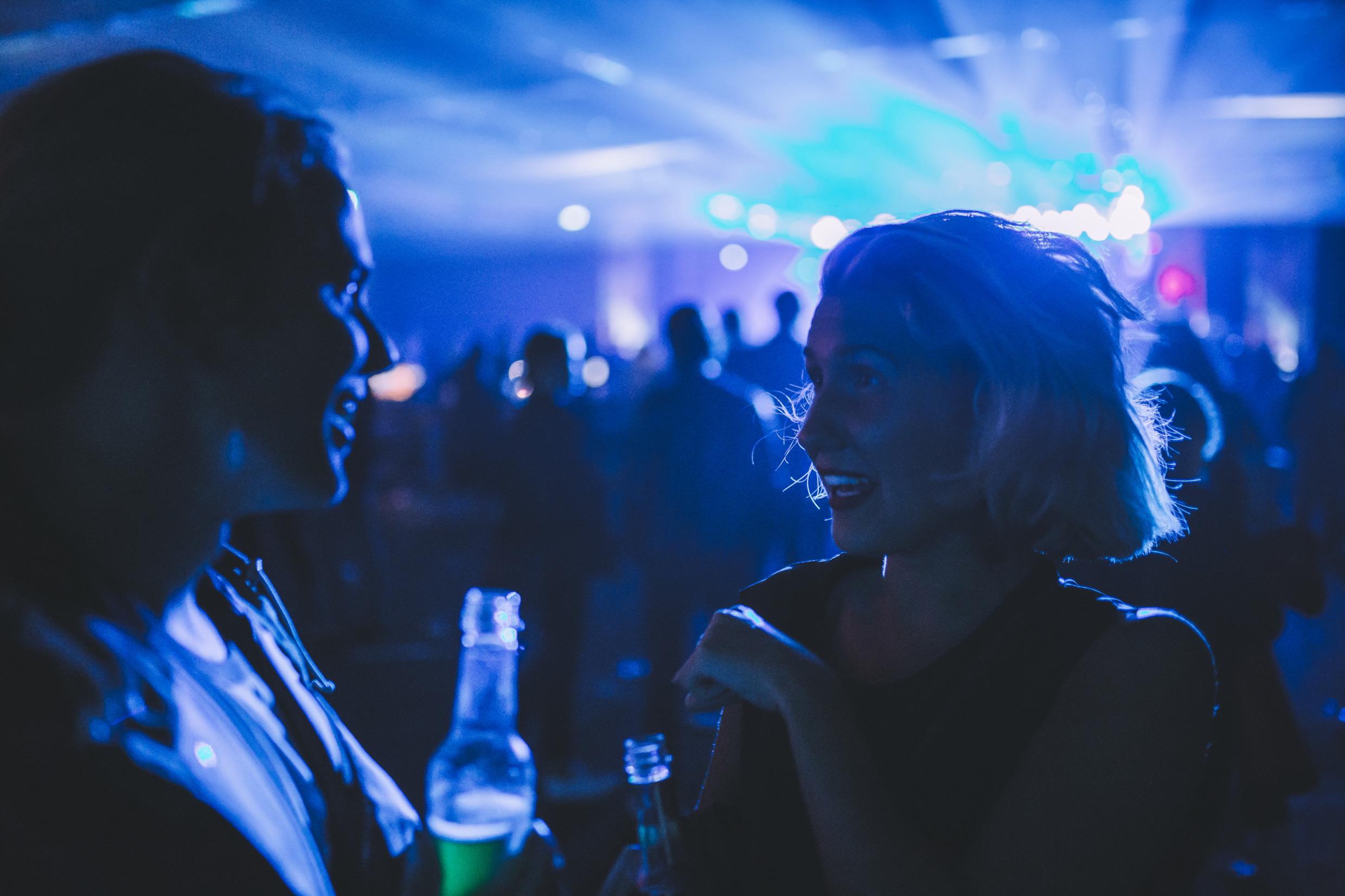 Two women holding drinks and talking at a nightclub in Gothenburg.