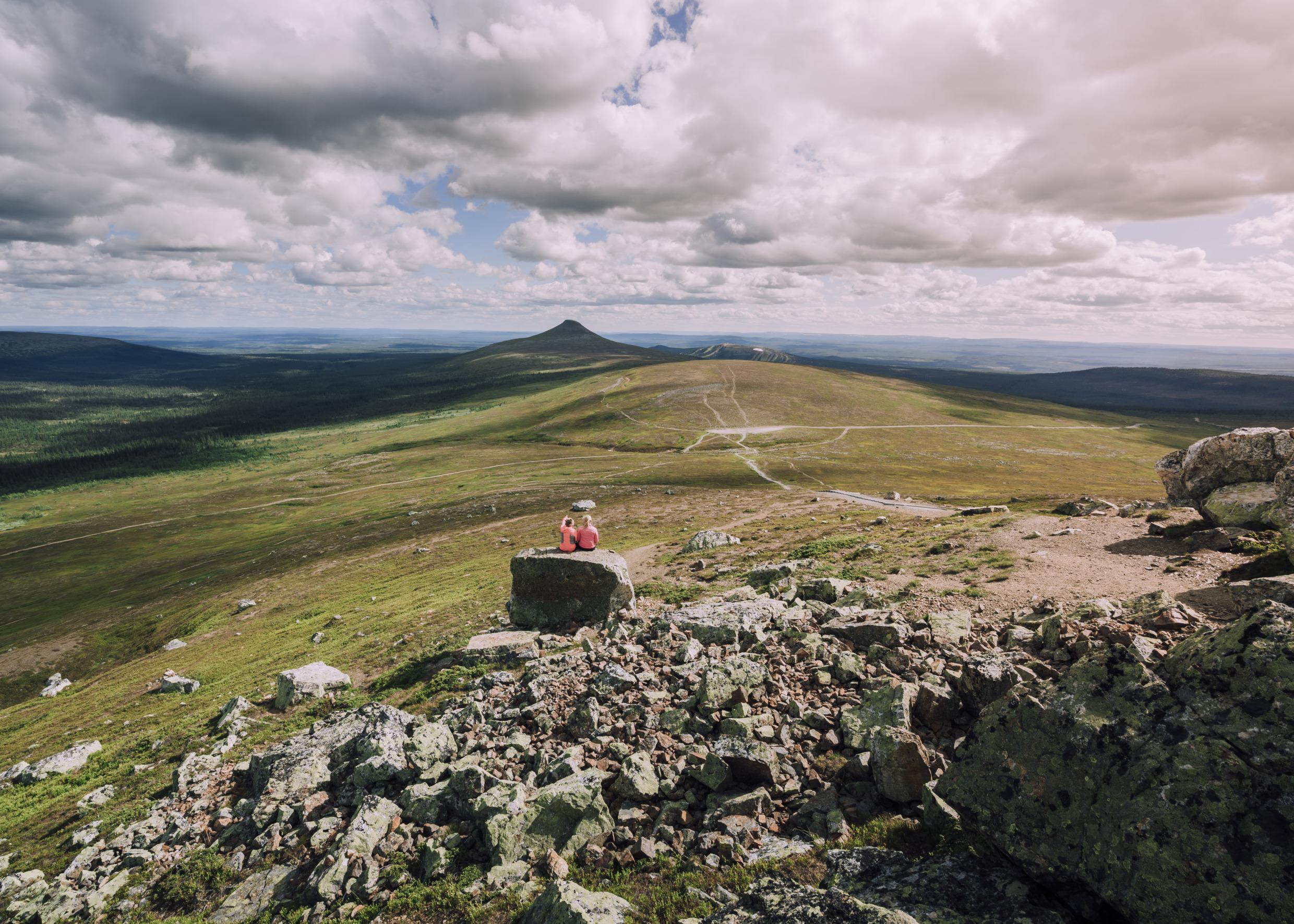Two people sitting on a rock looking at the mountains of Idre.