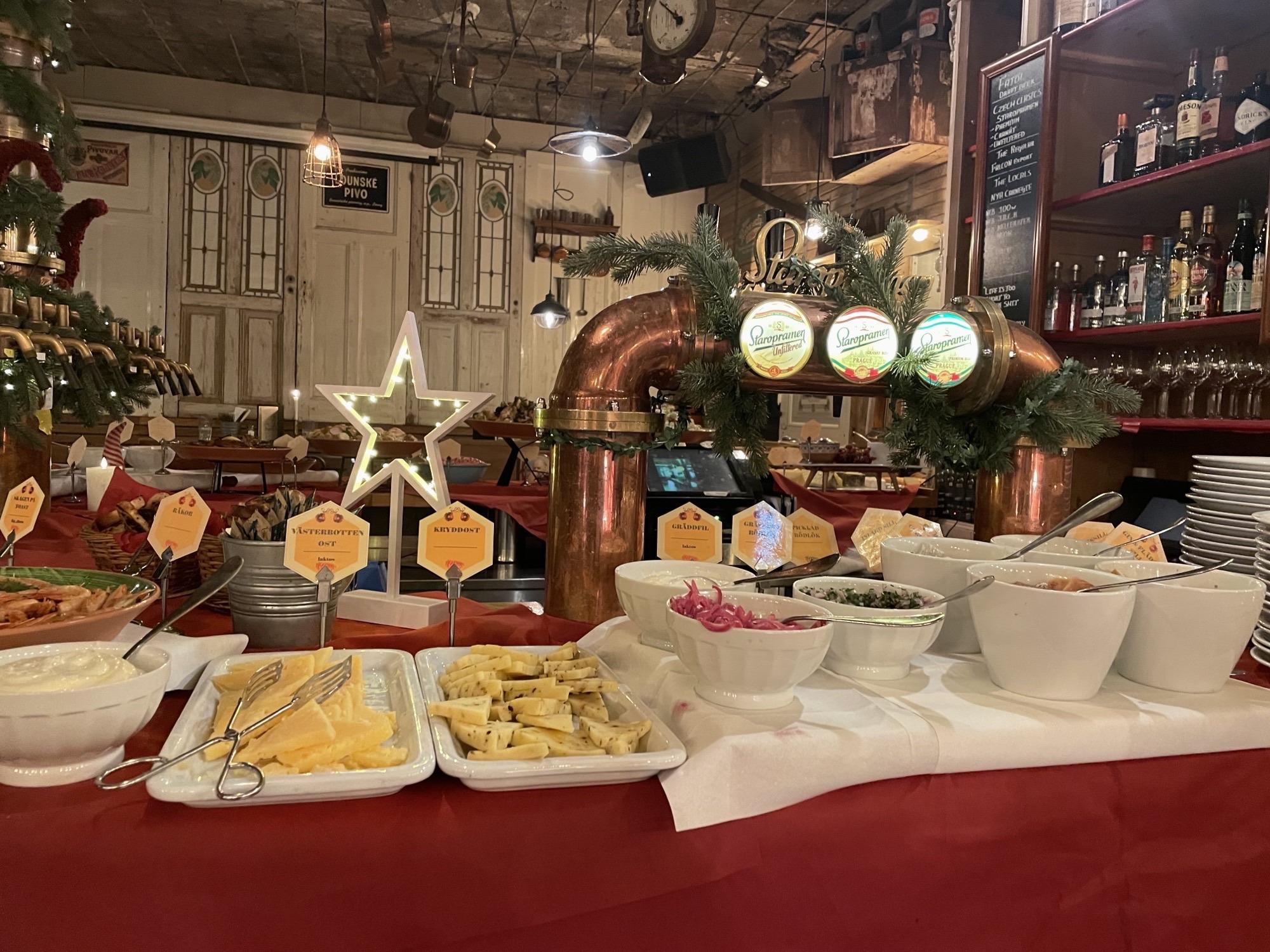 Le comptoir d'un bar recouvert d'une nappe rouge et de bols et récipients blancs contenant de la nourriture suédoise traditionnelle.