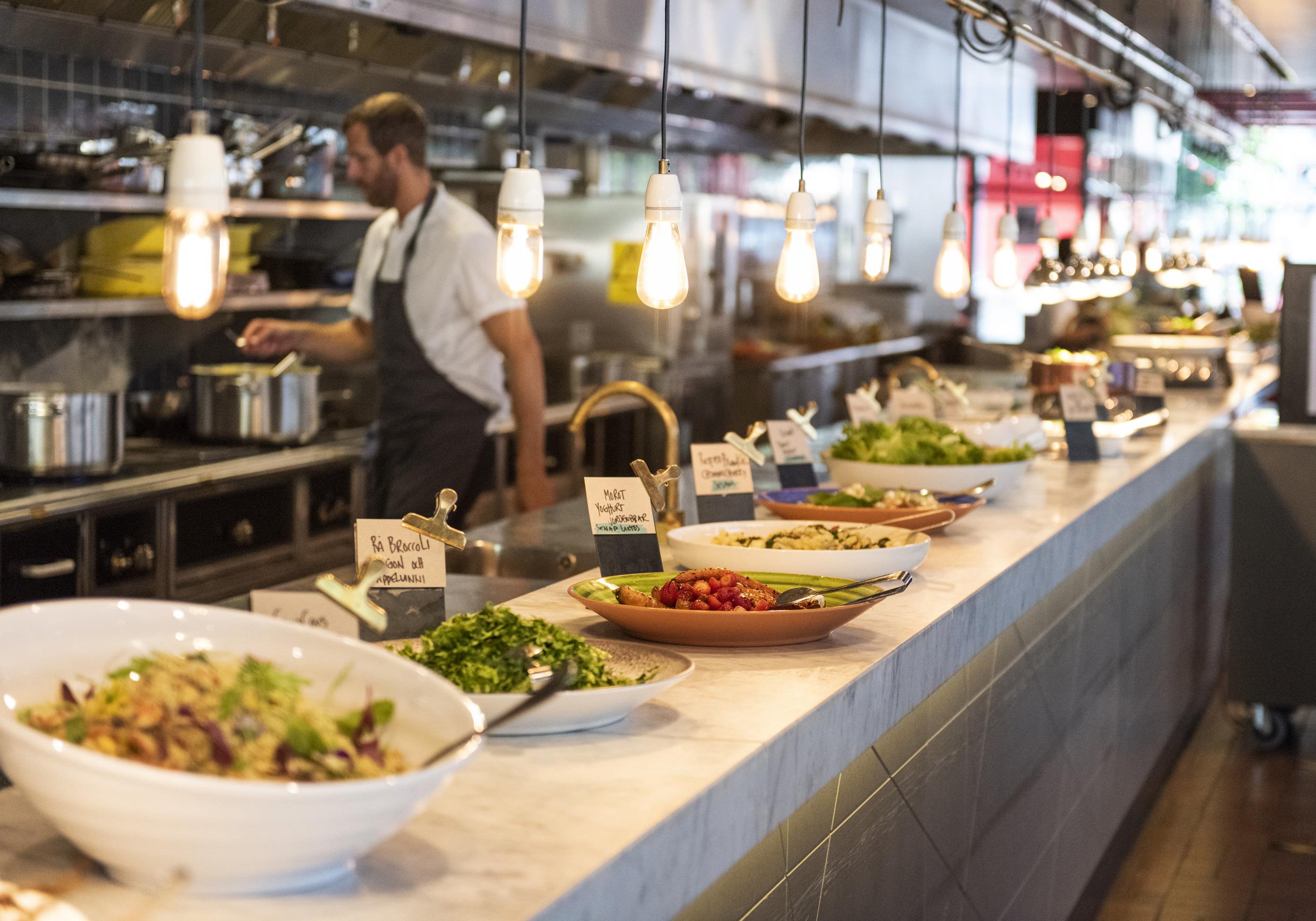Des assiettes remplies de nourriture sont posées sur un comptoir devant une cuisine ouverte dans un restaurant.