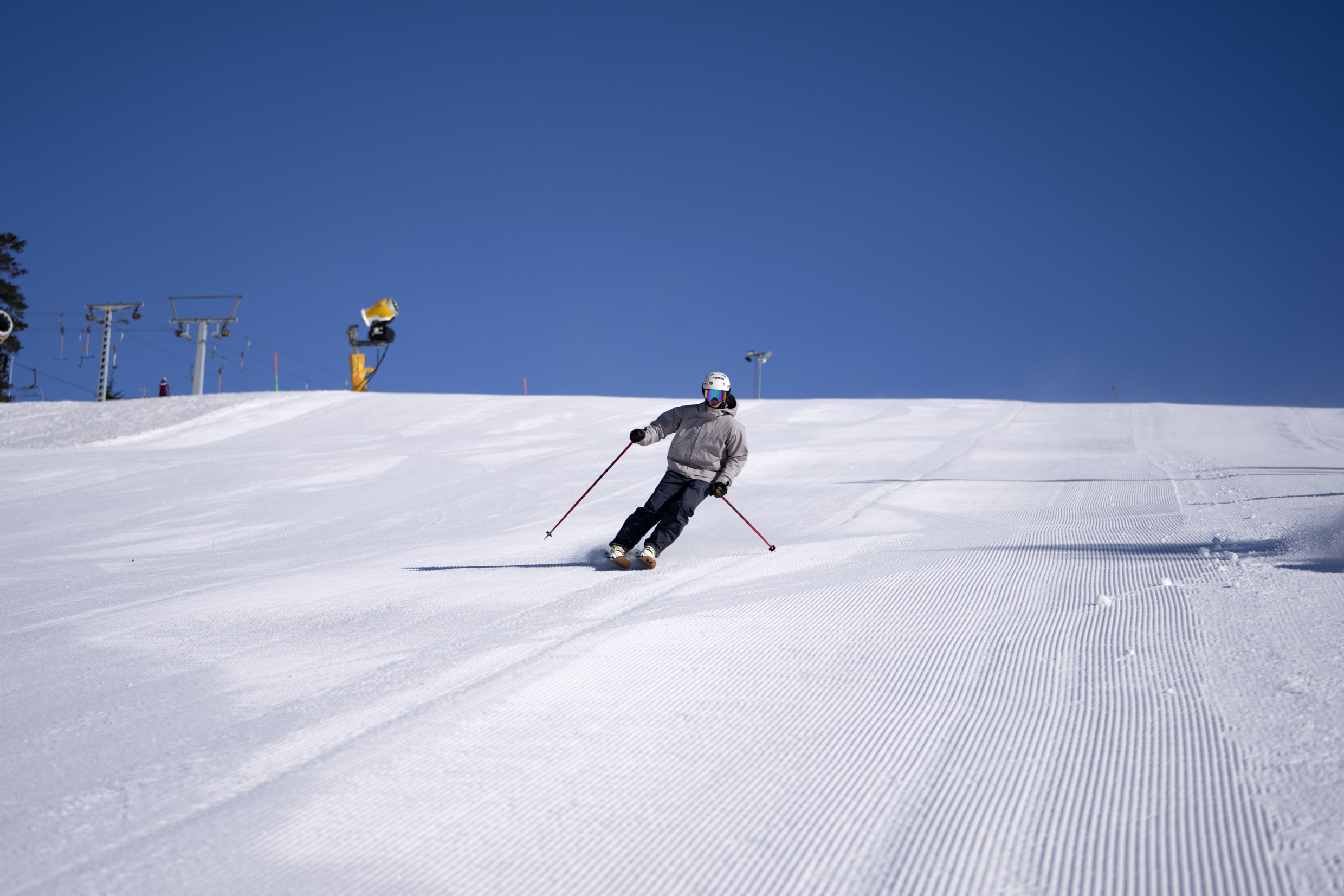 A person is downhill skiing on a sunny winter day. Grönklitt