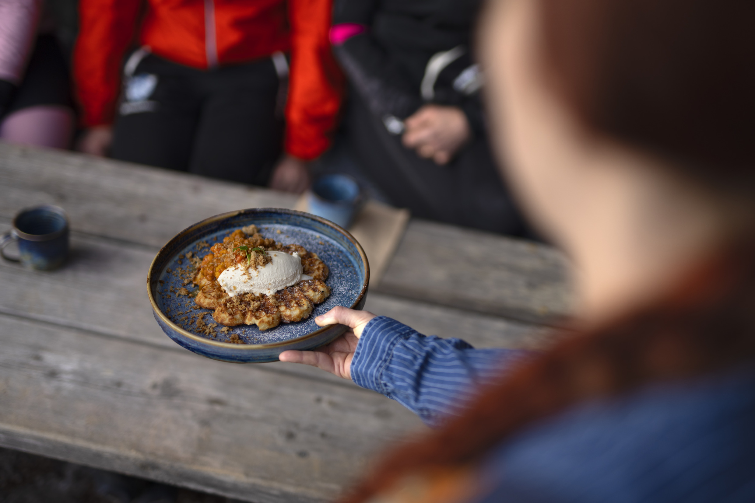 Eine Person reicht einer anderen Person einen Teller mit Waffeln.