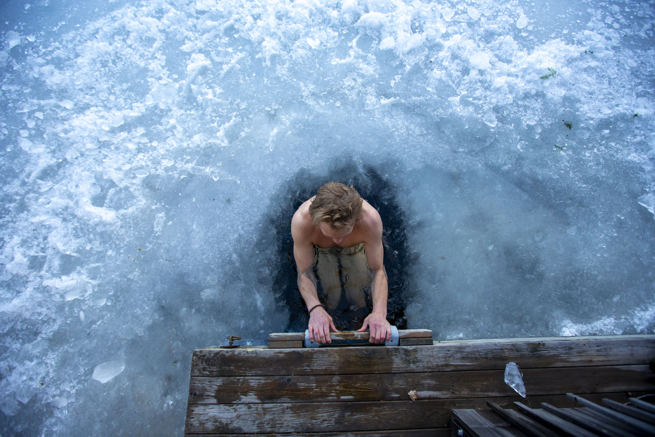 A man winter bathing in a sawed-out hole in the ice.