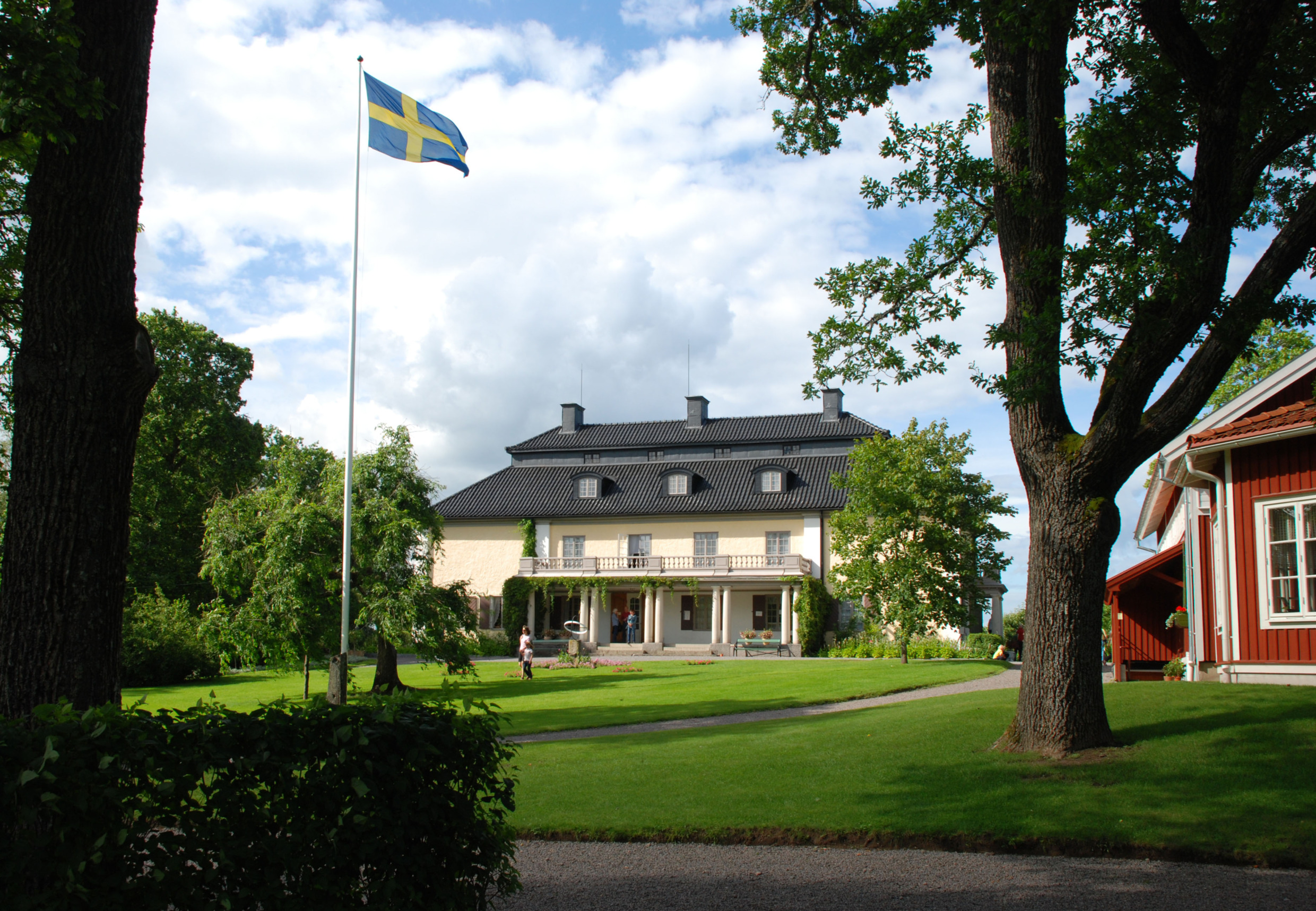 Yellow manor house with black roof and Swedish flag in the garden, Mårbacka – the home of author Selma Lagerlöf in Sunne, Sweden.