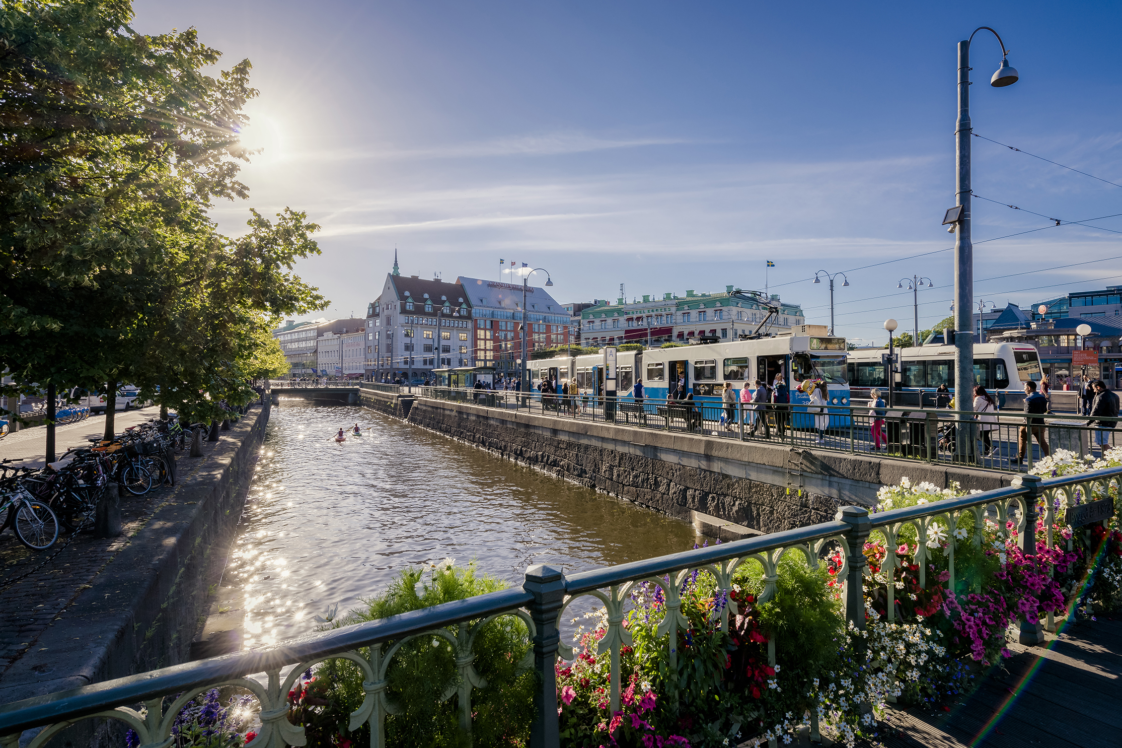 A blue tram travelling alongside a canal in central Gothenburg.