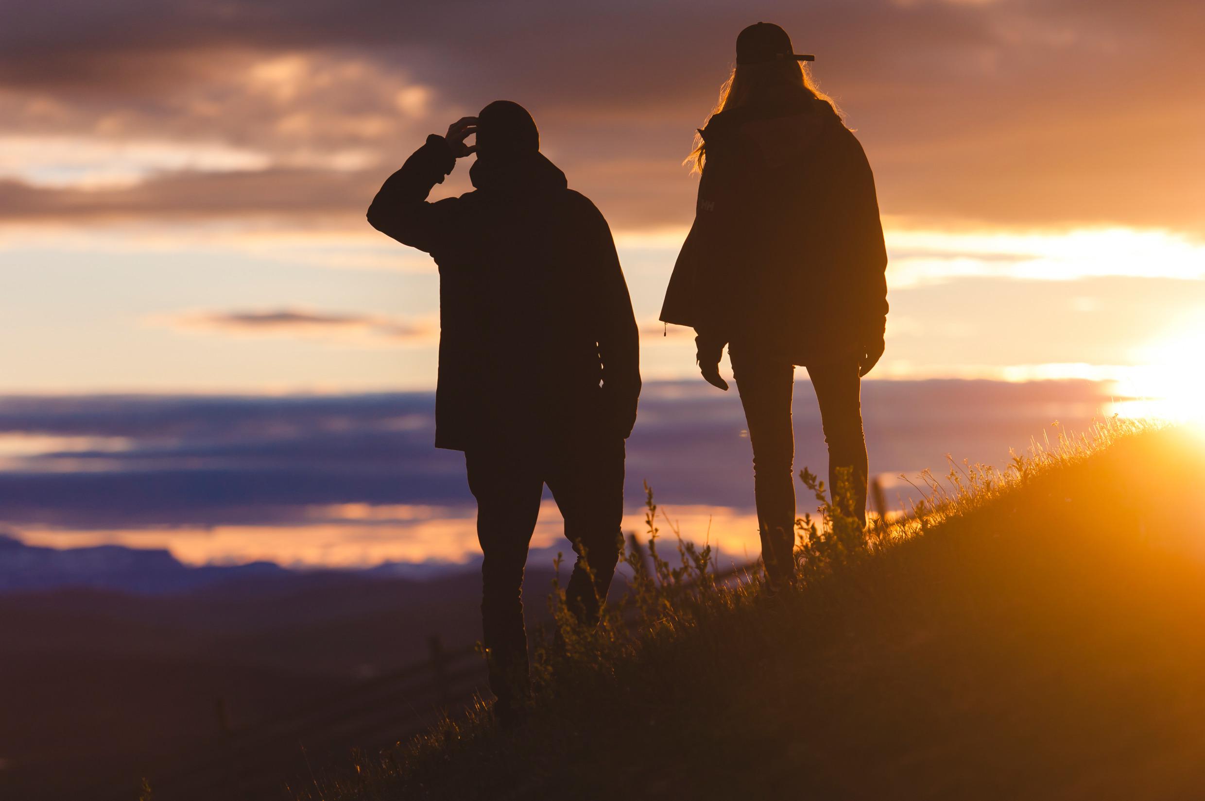Two people enjoy the Midnight Sun from Luossavaara outside Kiruna. The view is of the Scandinavian Mountain range.