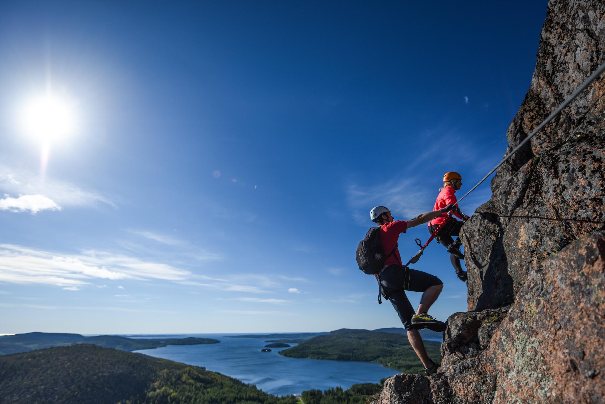 Zwei Personen besteigen einen Berg mit Blick auf den Archipel.