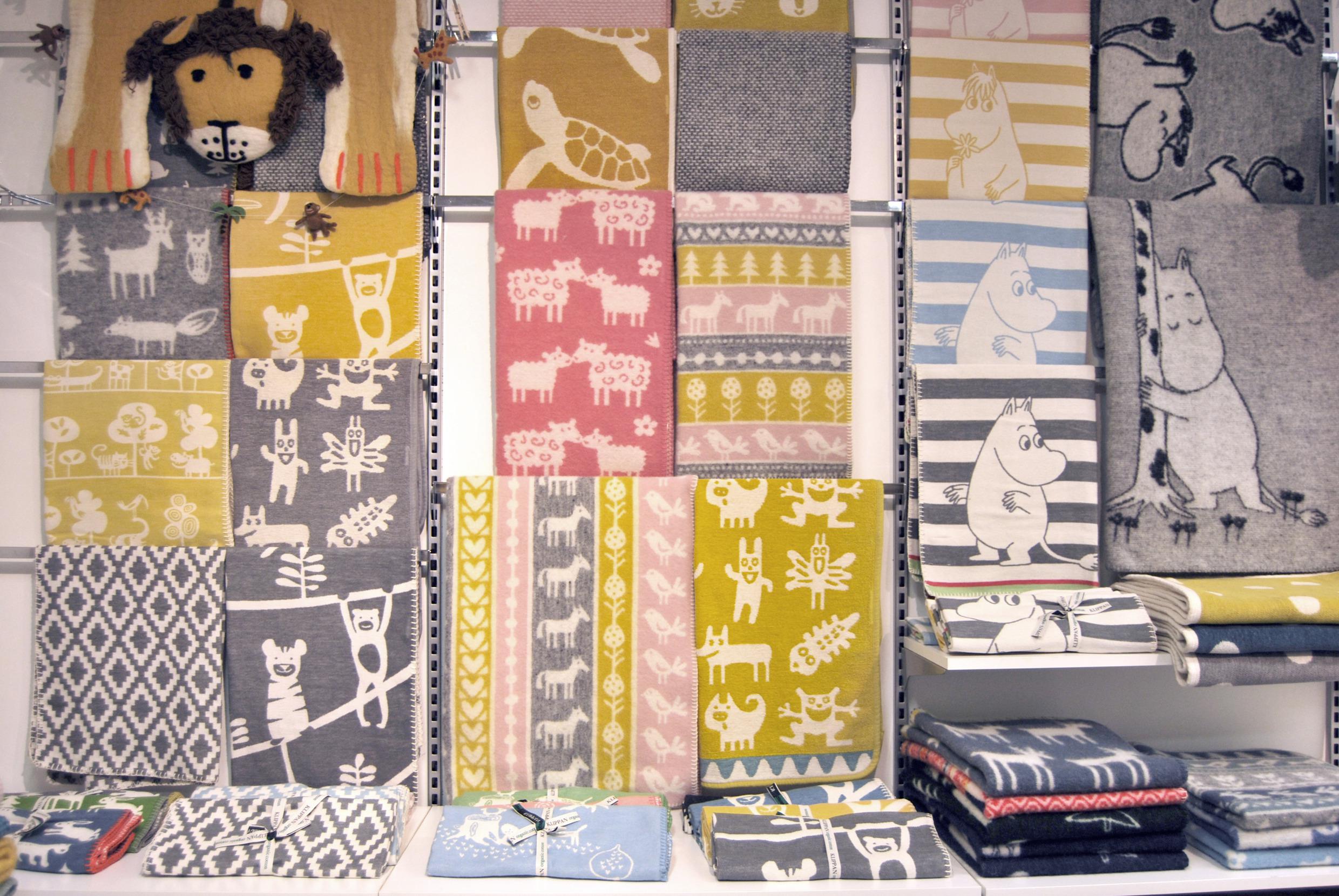 Wool blankets in different patterns hang on the wall in a store.