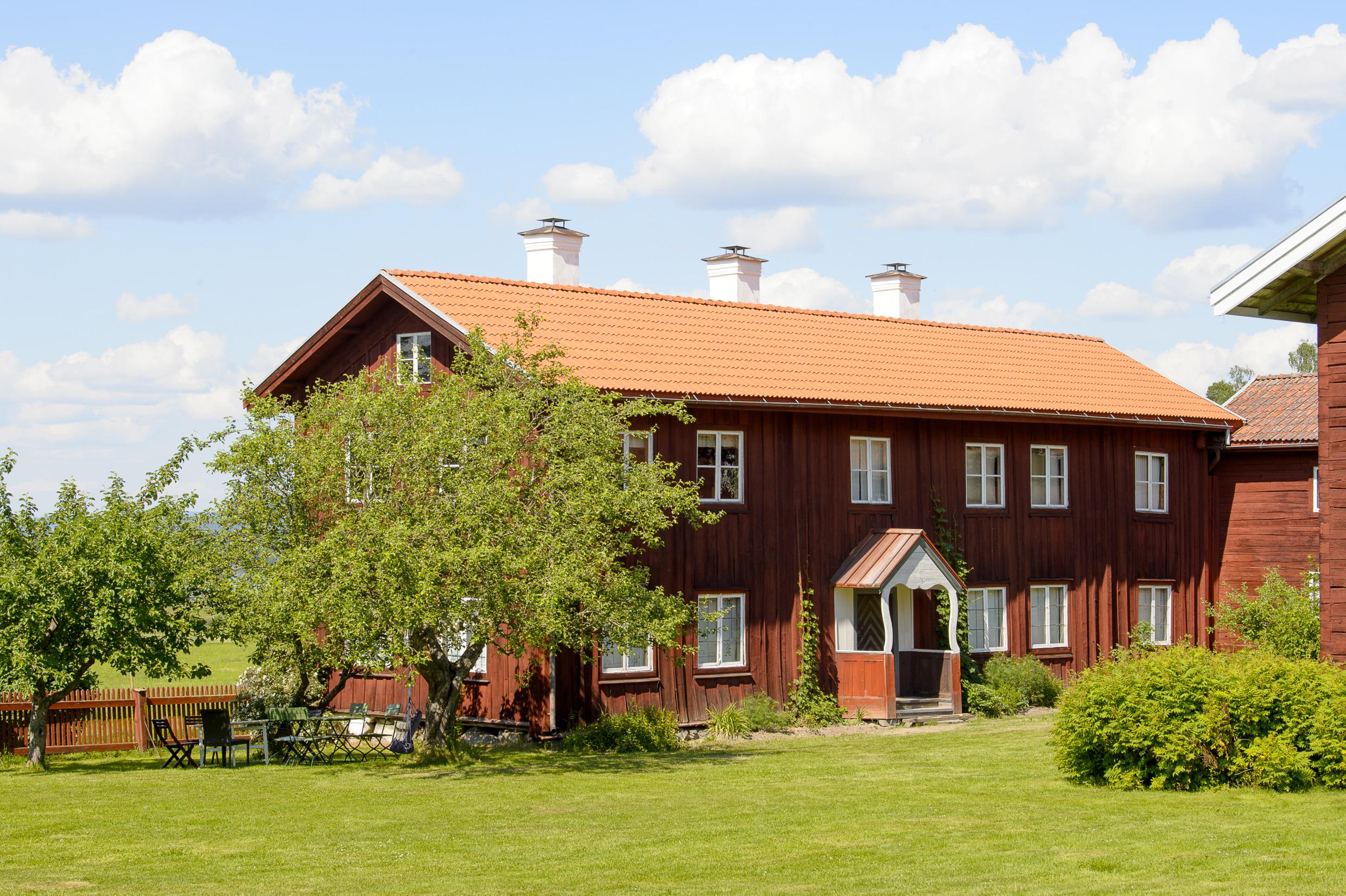 Une ferme rouge entourée de verdure en été.