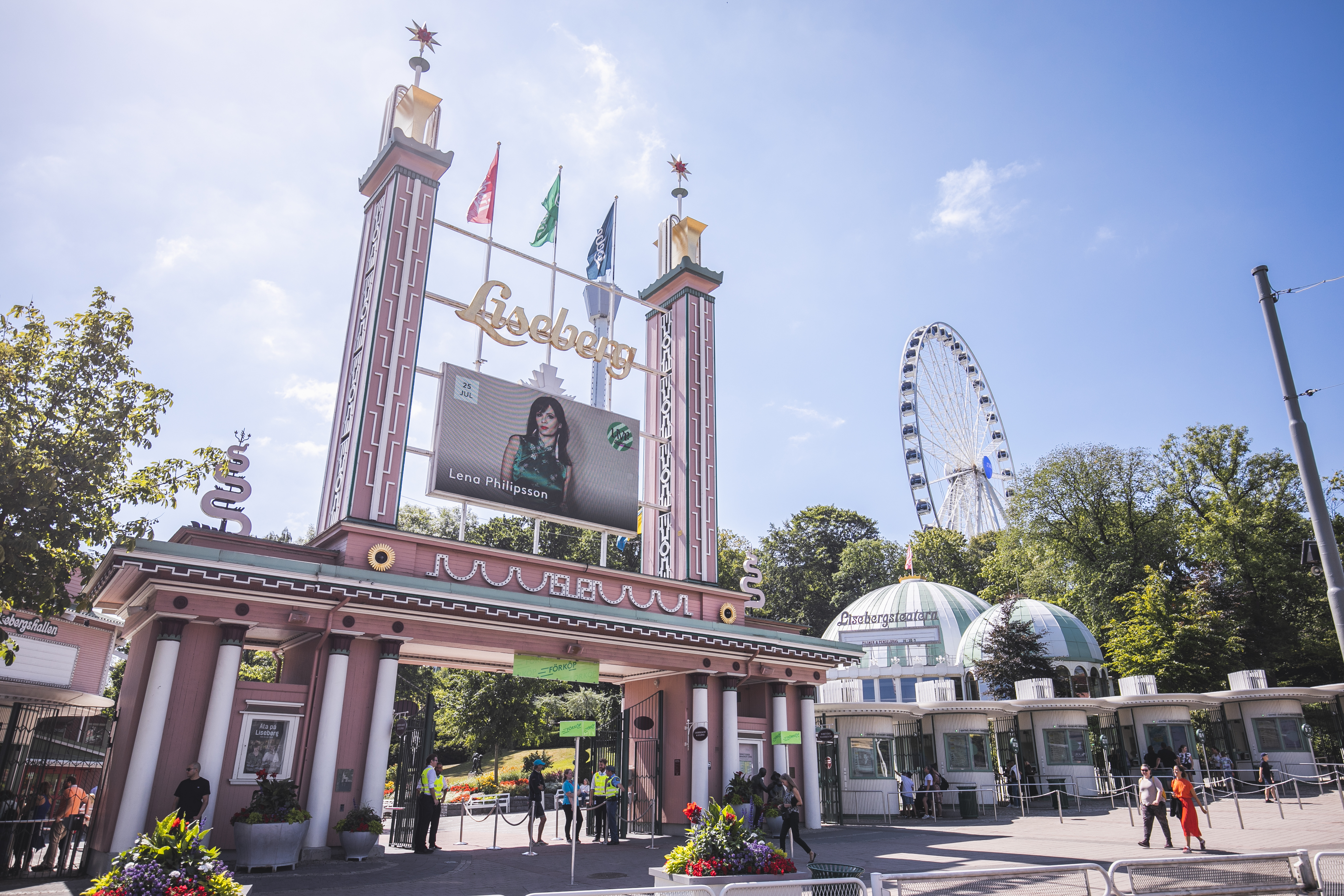 Eingangstor zum Vergnügungspark Liseberg in Göteborg, im Hintergrund ein Riesenrad und Menschen, die am Eingang ankommen.
