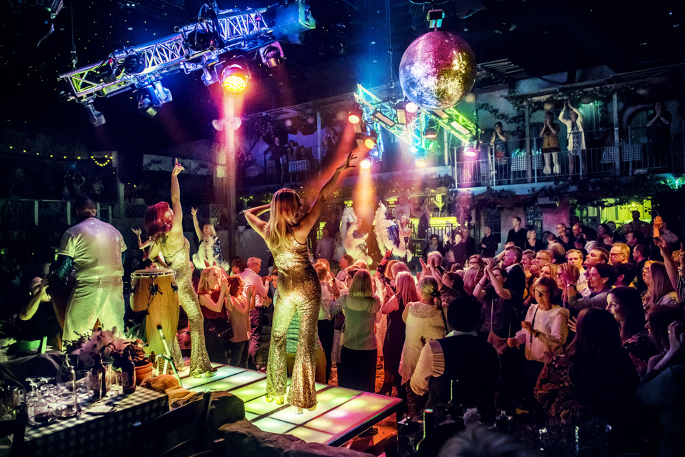 Musikerinnen stehen auf einer Bühne, während das Publikum darunter tanzt.