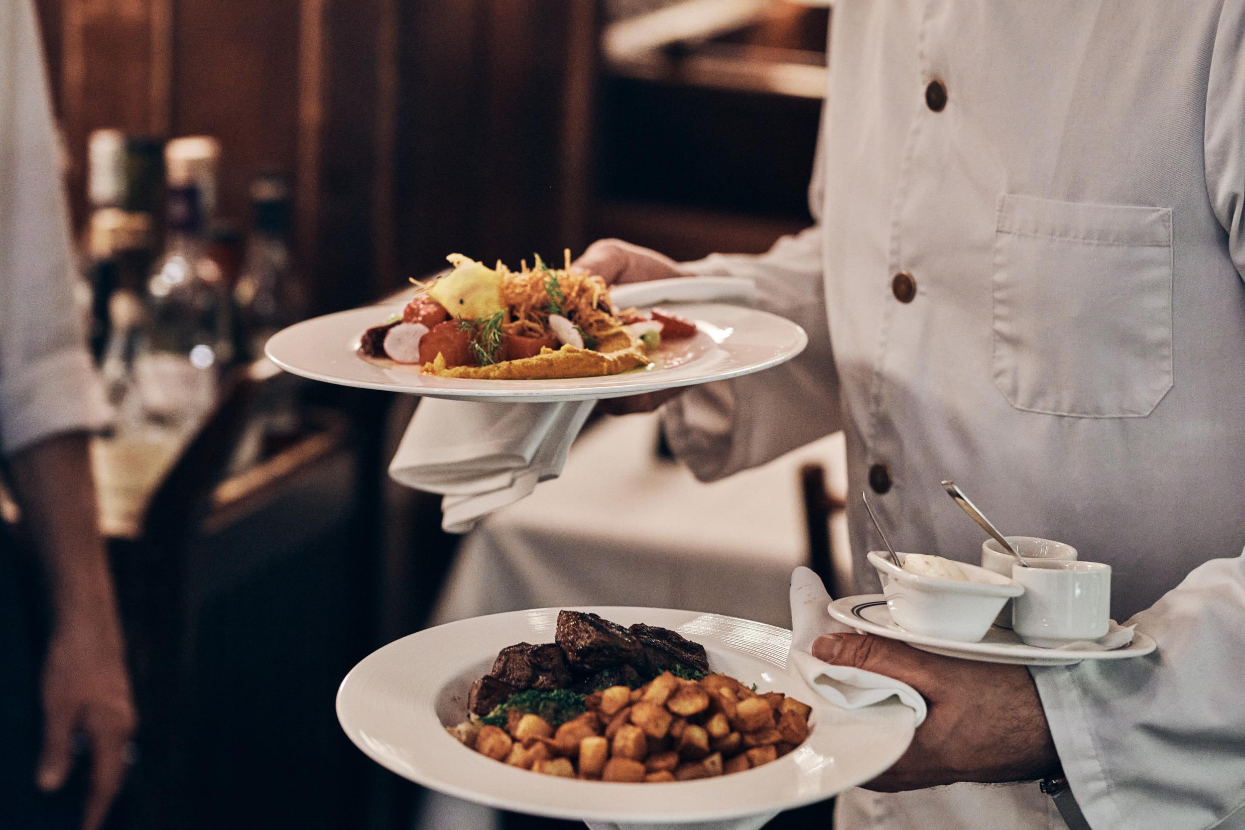 Een ober die borden met eten vasthoudt.