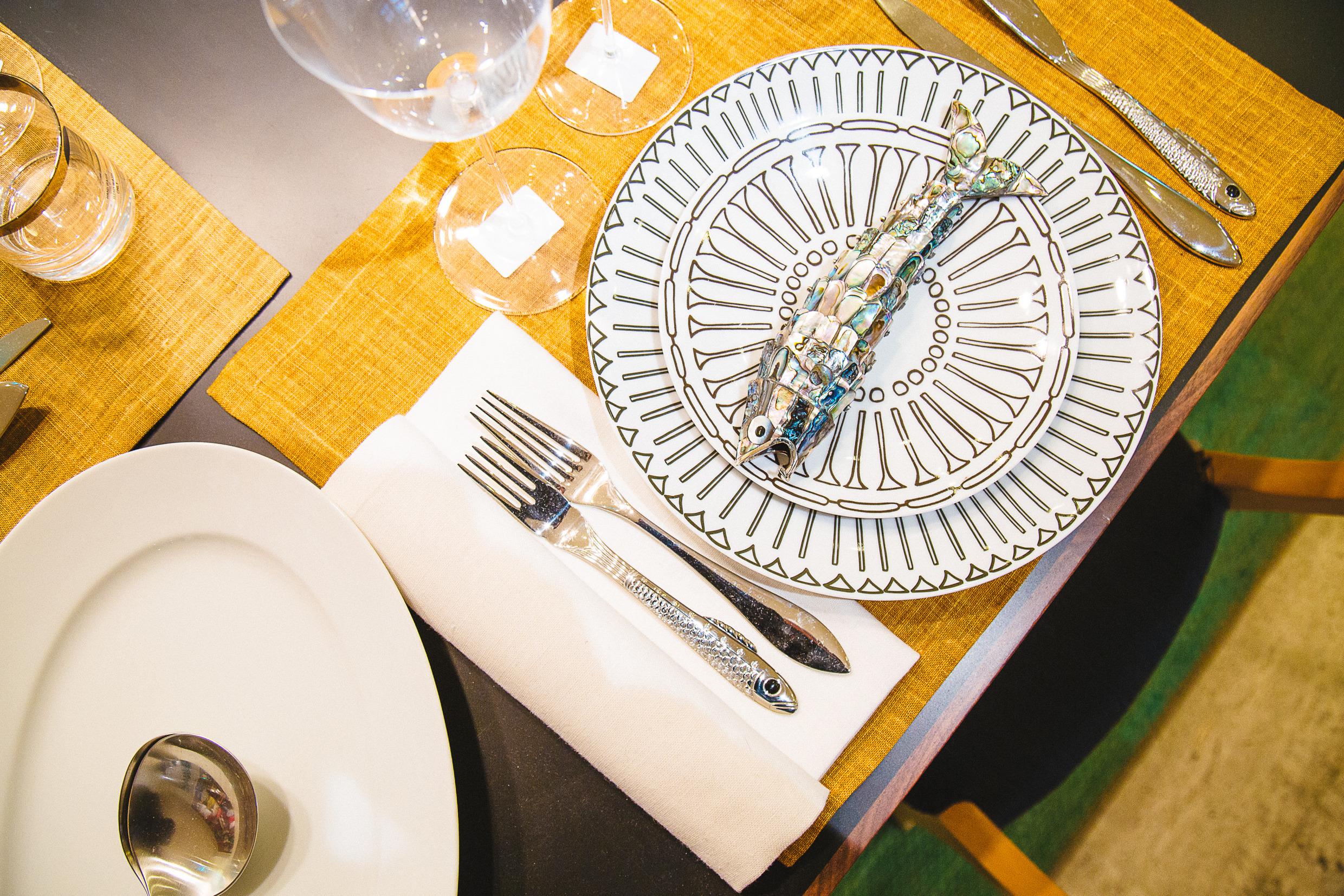 Vue en hauteur d'une table avec des sets de table jaunes et le couvert posé dessus.