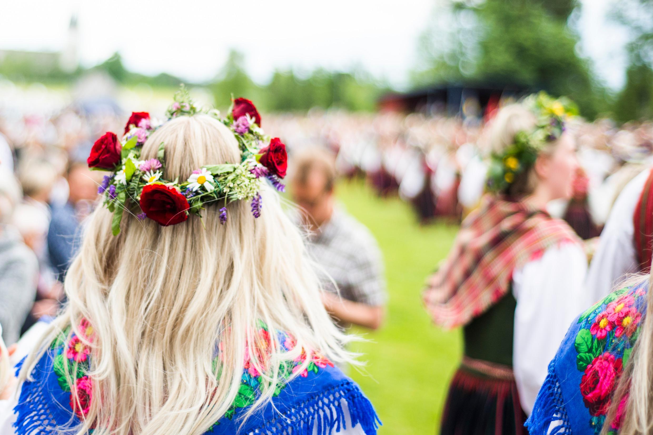 Een menigte mensen in Dalarna, waarvan sommigen midzomerbloemenkransen in hun haar dragen.
