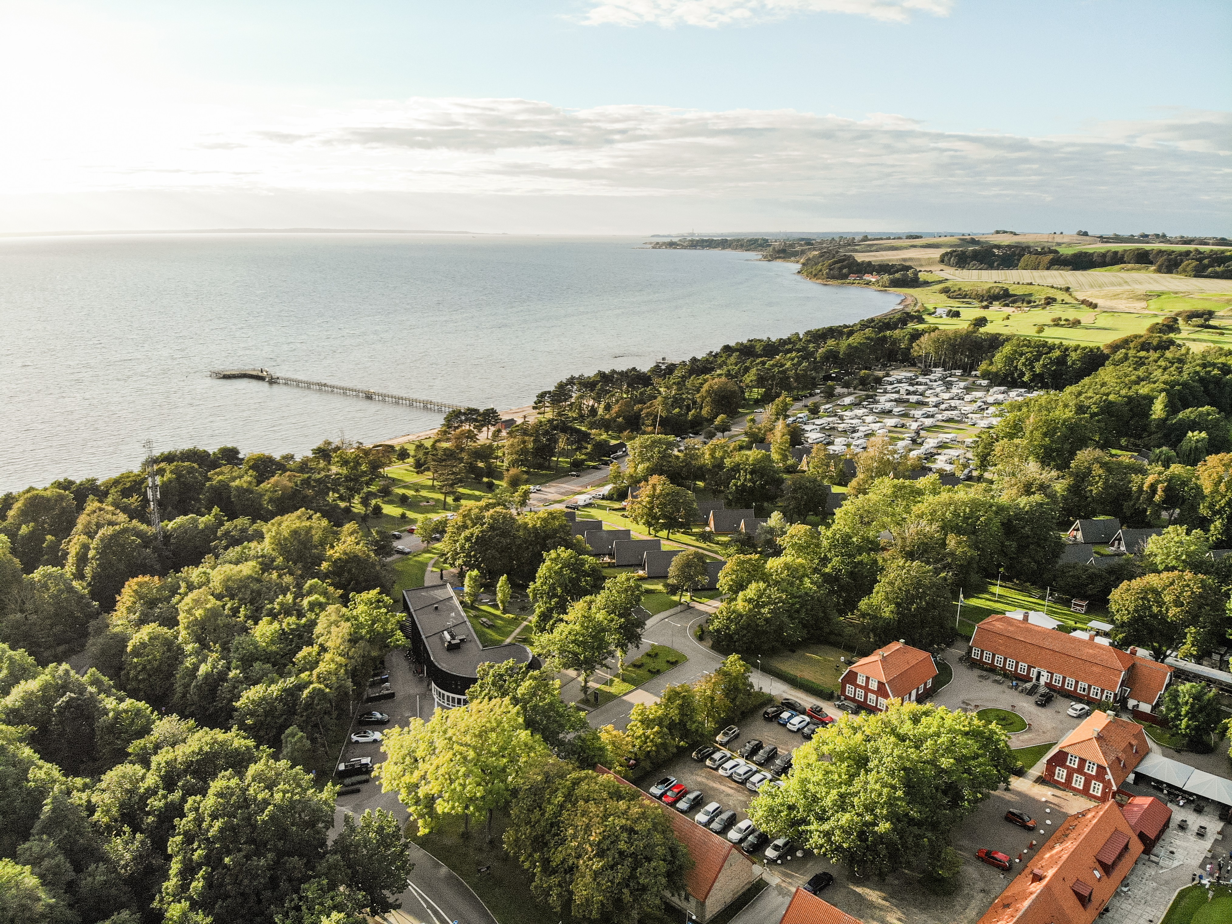 Aerial view of Borstahusen Campingresort in Skåne with campsite, coastline and jetty by the sea.