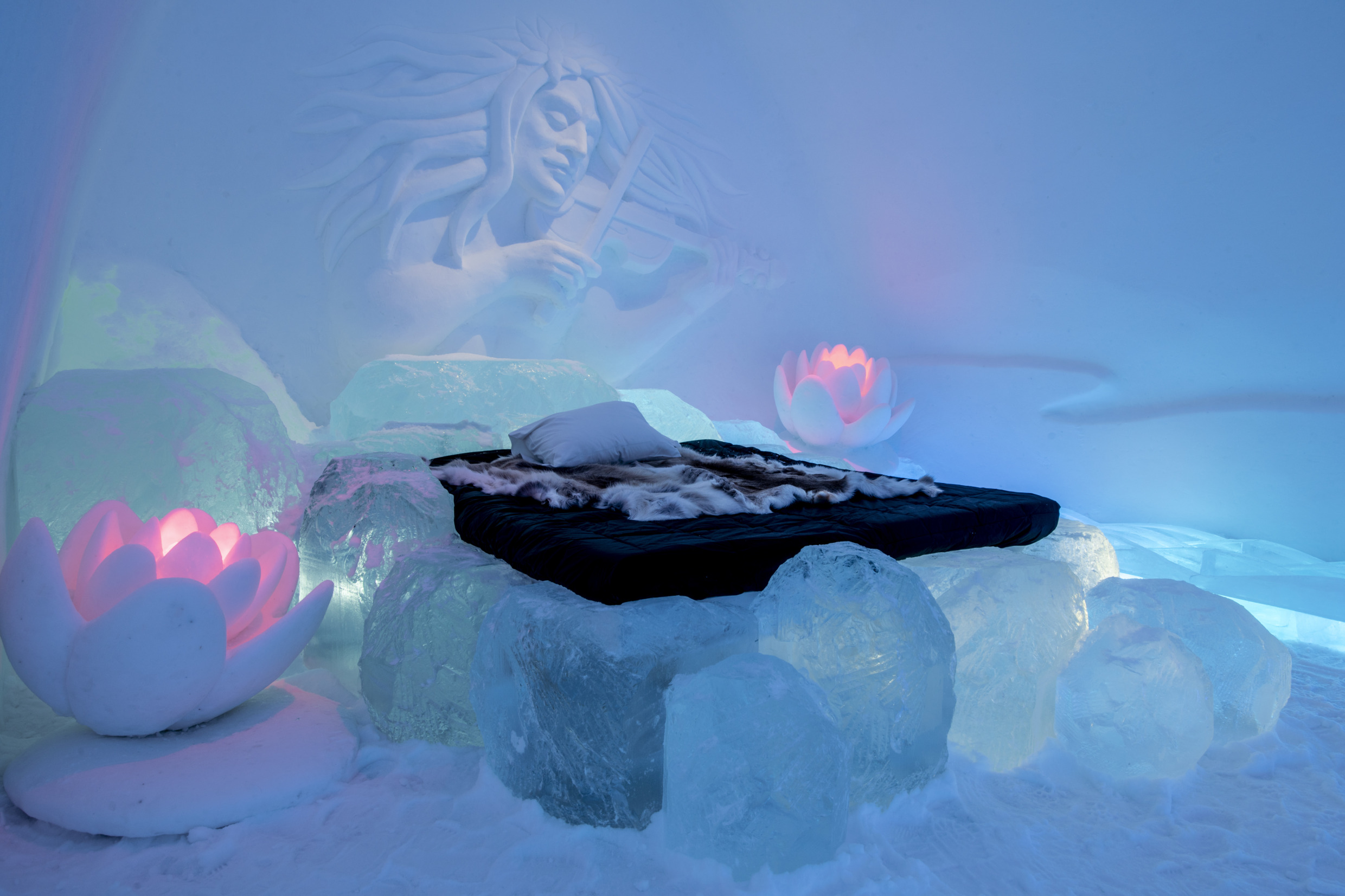 A stunning suite at the Icehotel in Jukkasjärvi, with the Näcken elegantly carved into the wall and delicate water lilies sculpted from frozen materials.