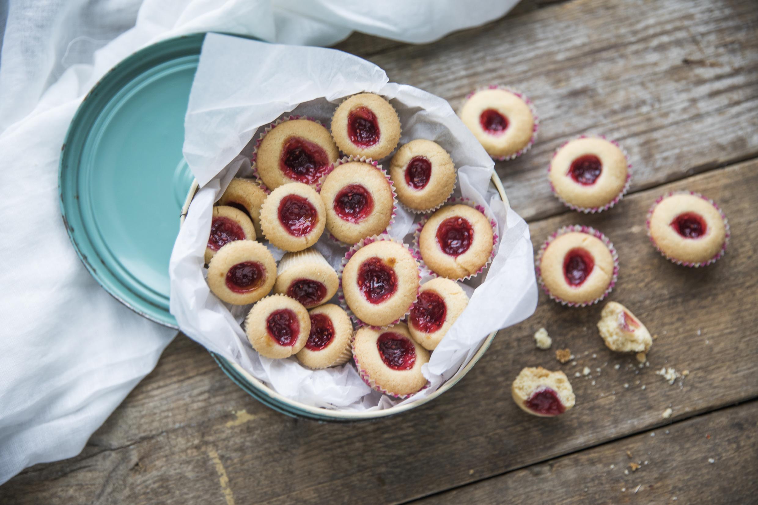 Des grottes à la framboise sont disposés dans un plat de cuisson sur une table. Quelques biscuits sont placés directement sur la table en bois.