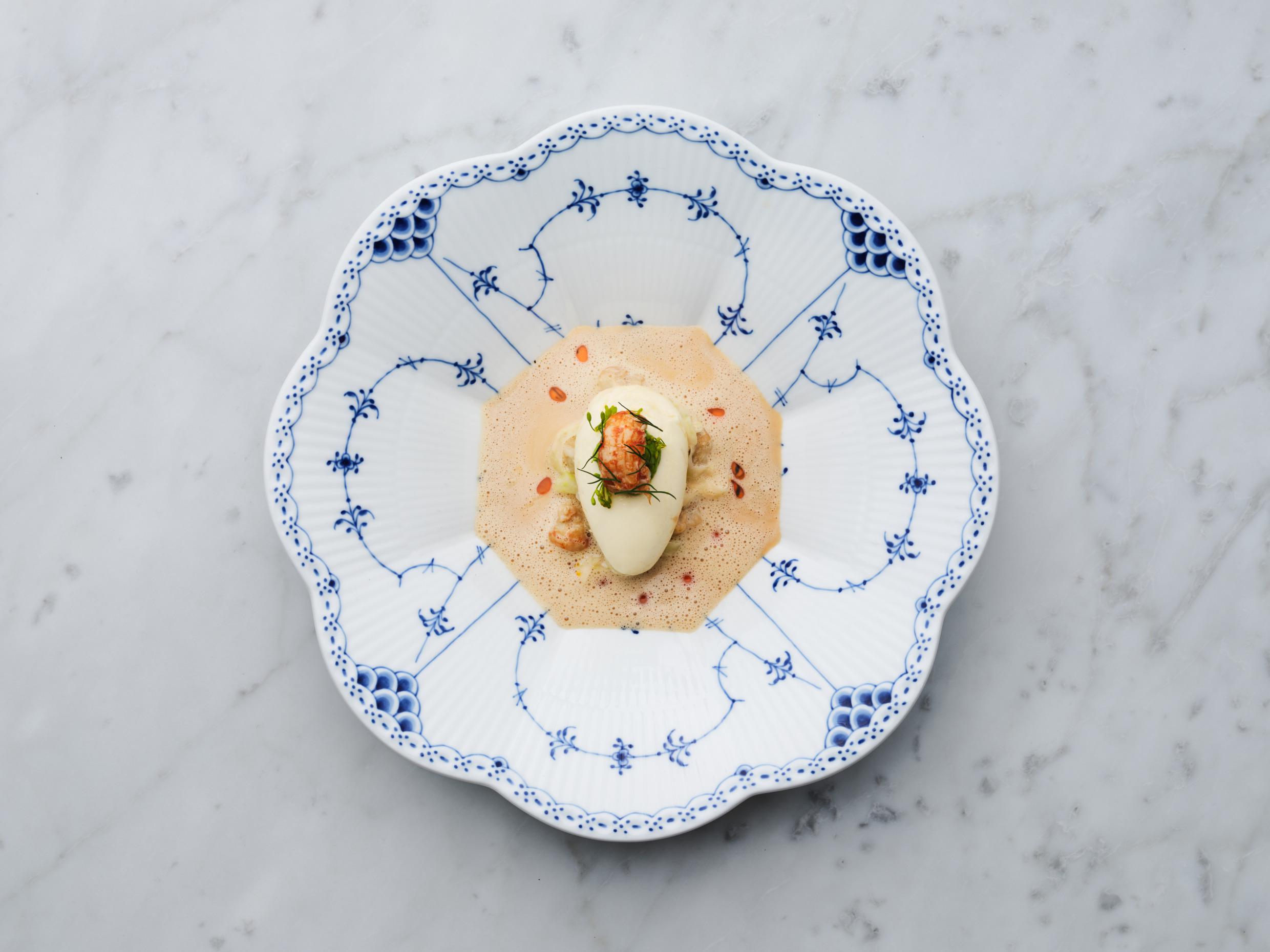 Netjes geplaatst eten op een wit bord met blauwe decoratieve patronen.