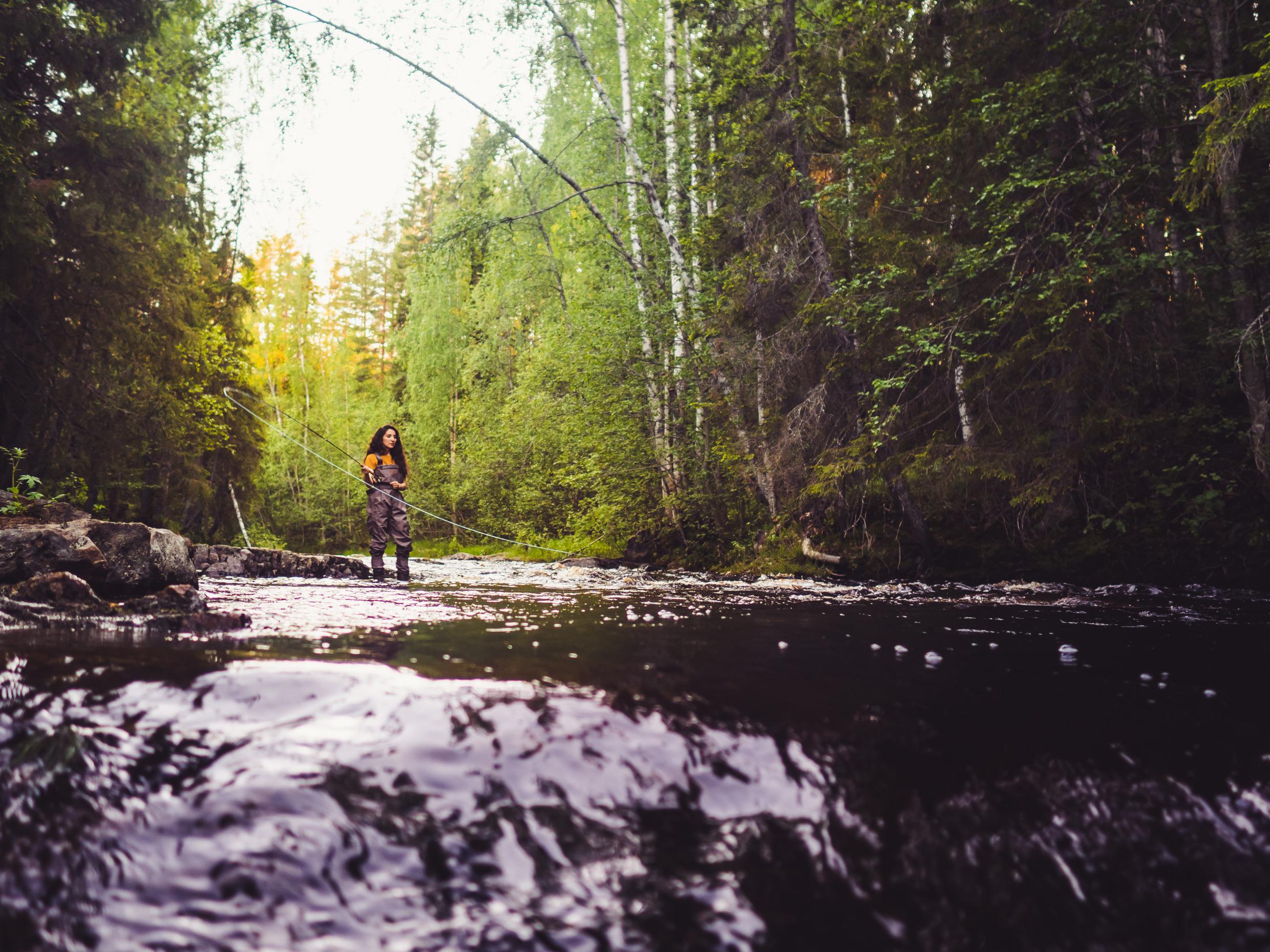 Eine Frau beim Fliegenfischen in einem Fluss.