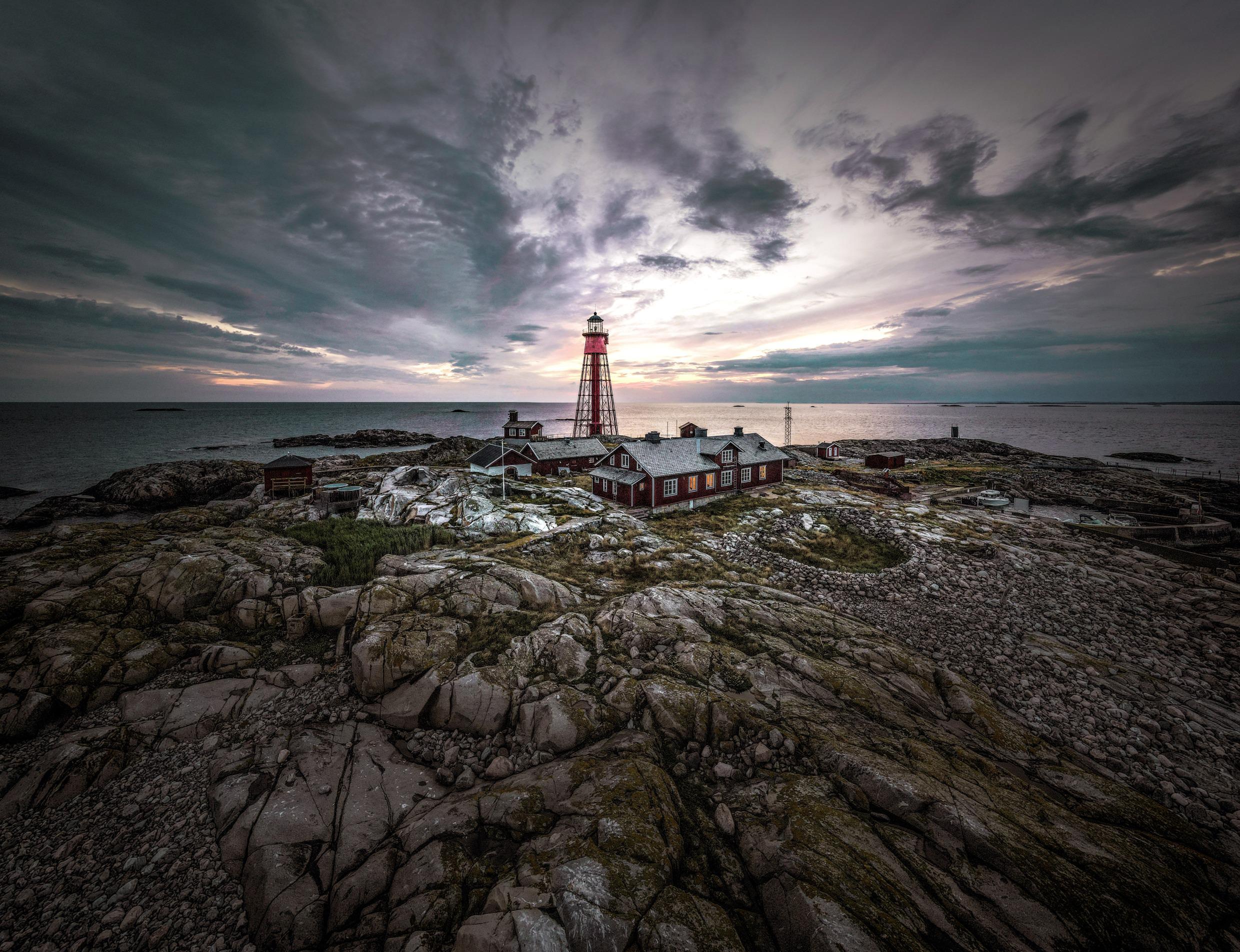 Vue sur un phare et quelques chalets rouges sur une petite île dans l'archipel de la côte Ouest.