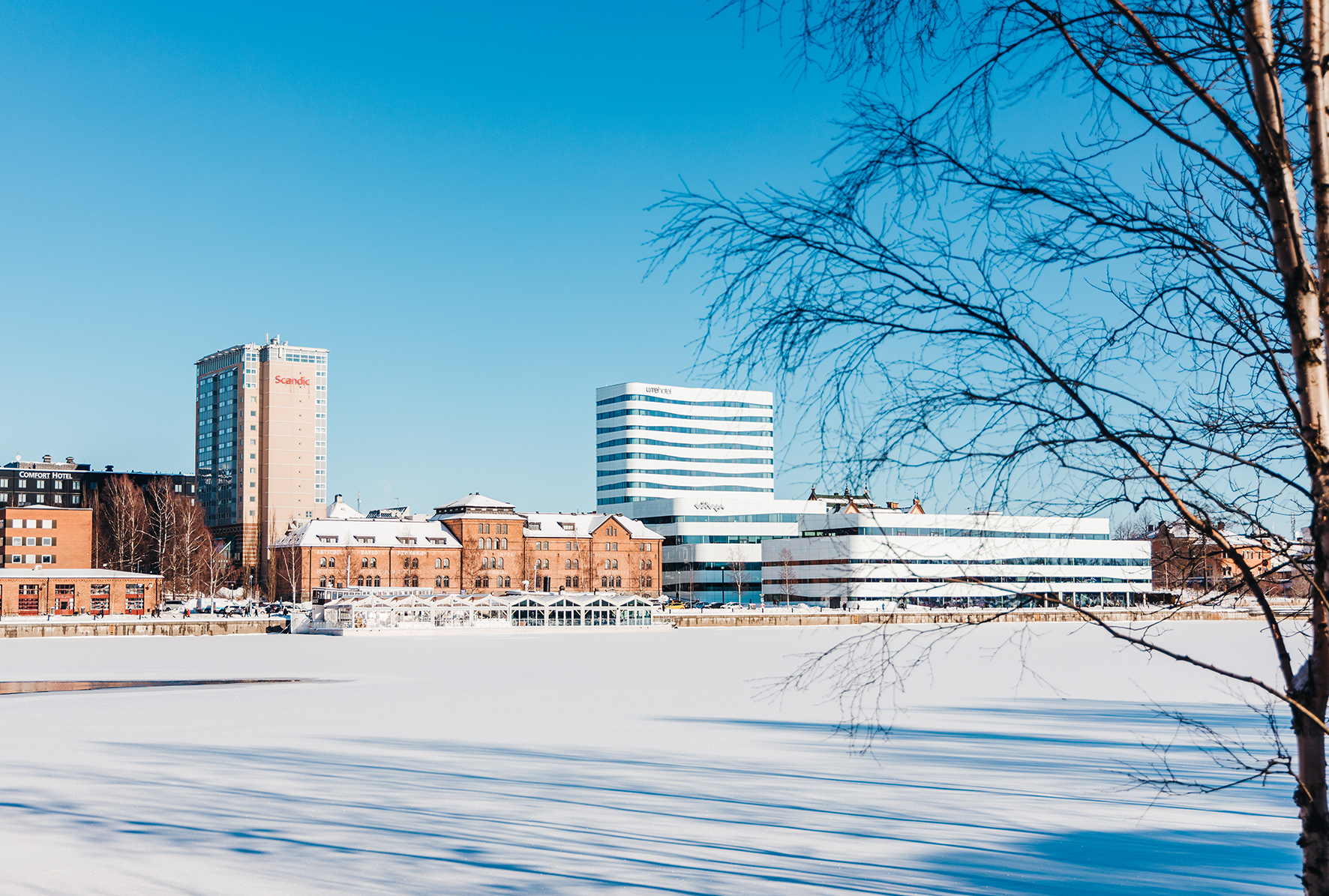 Väven cultural centre in Umeå, a white birch-inspired building beside the frozen Ume River in winter.