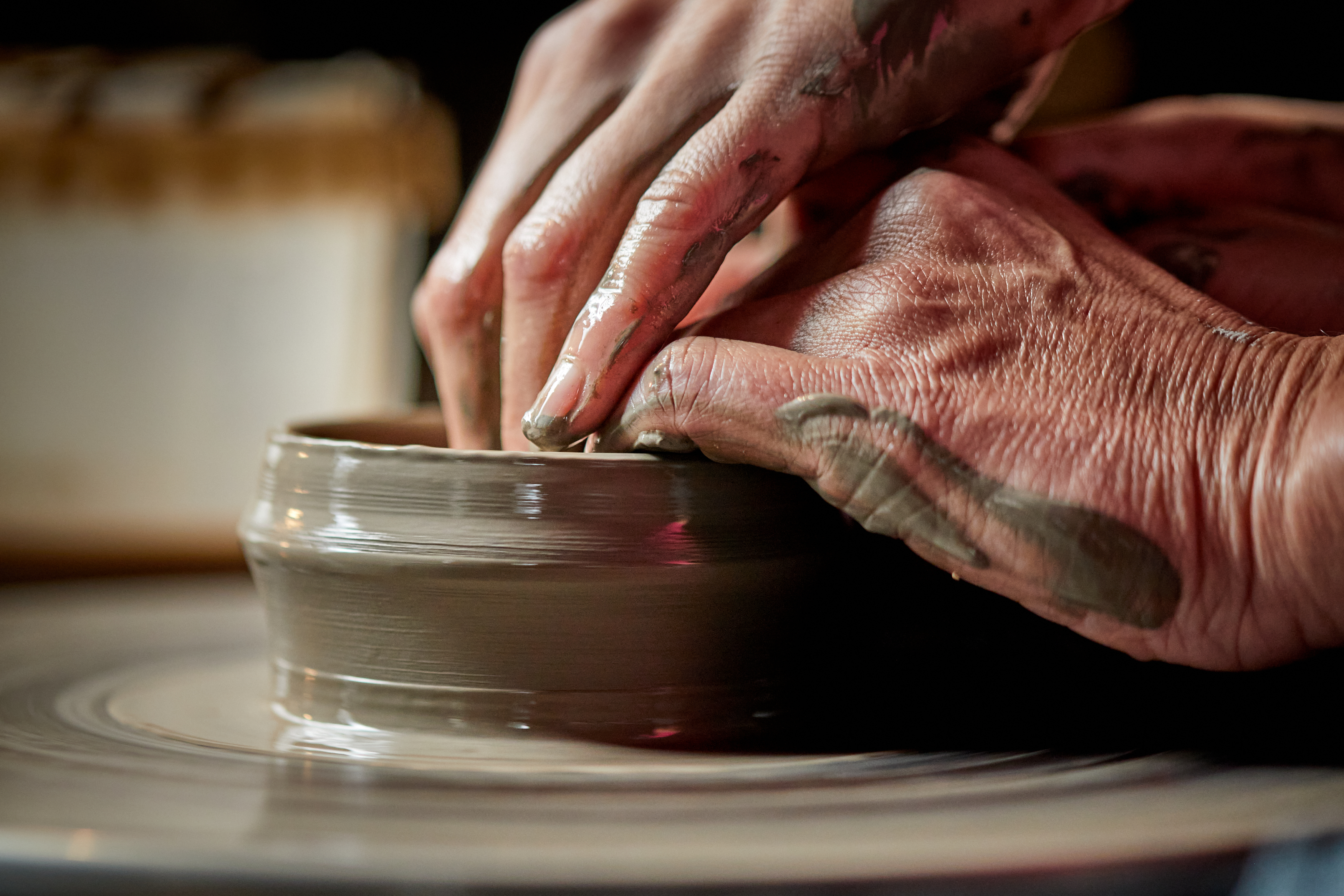 Hands shape clay on a pottery wheel at Wallåkra Stoneware Factory in Skåne.