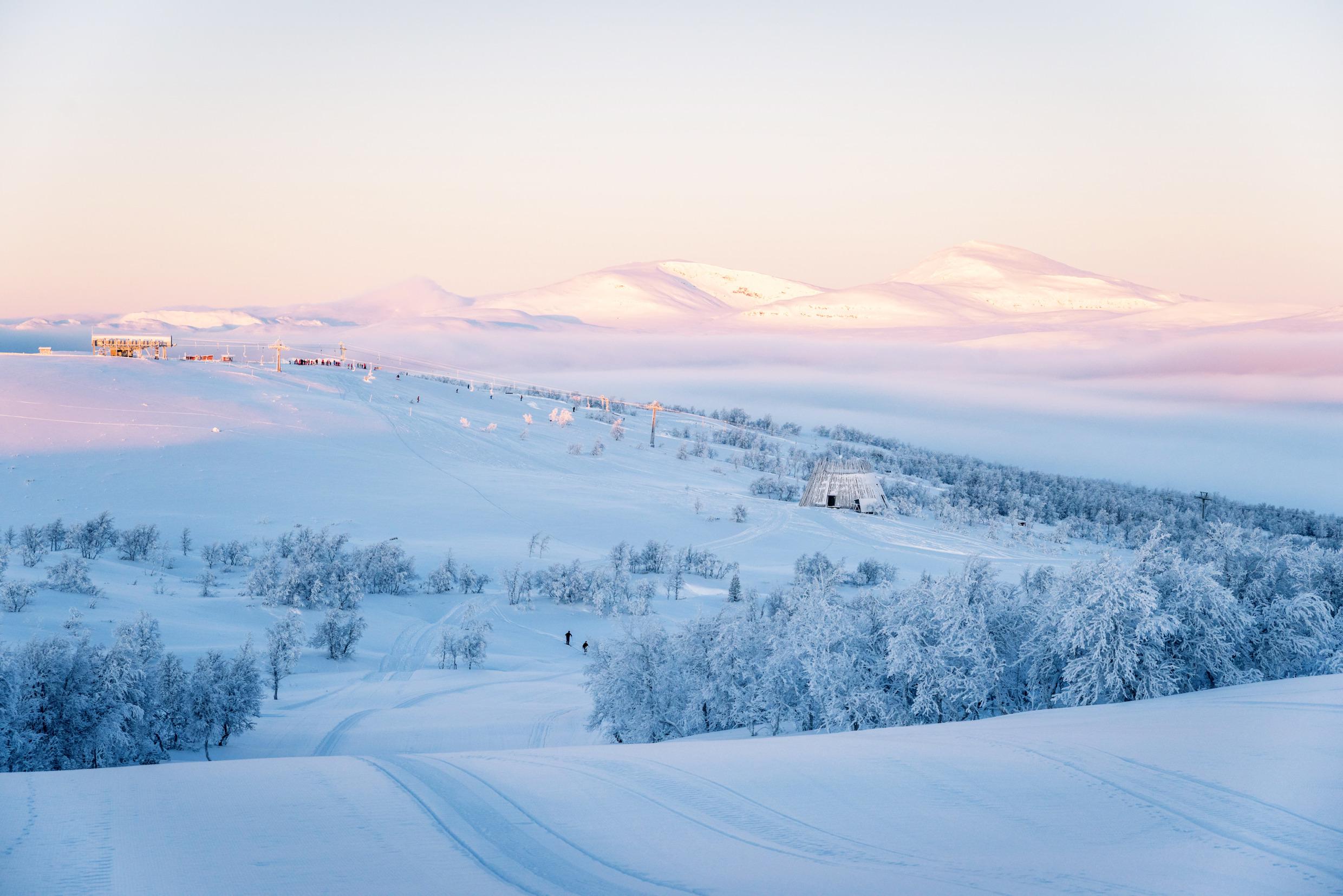 Uitzicht op een besneeuwd gebied en een langlaufloipe. Ramundberget ligt in de achtergrond.