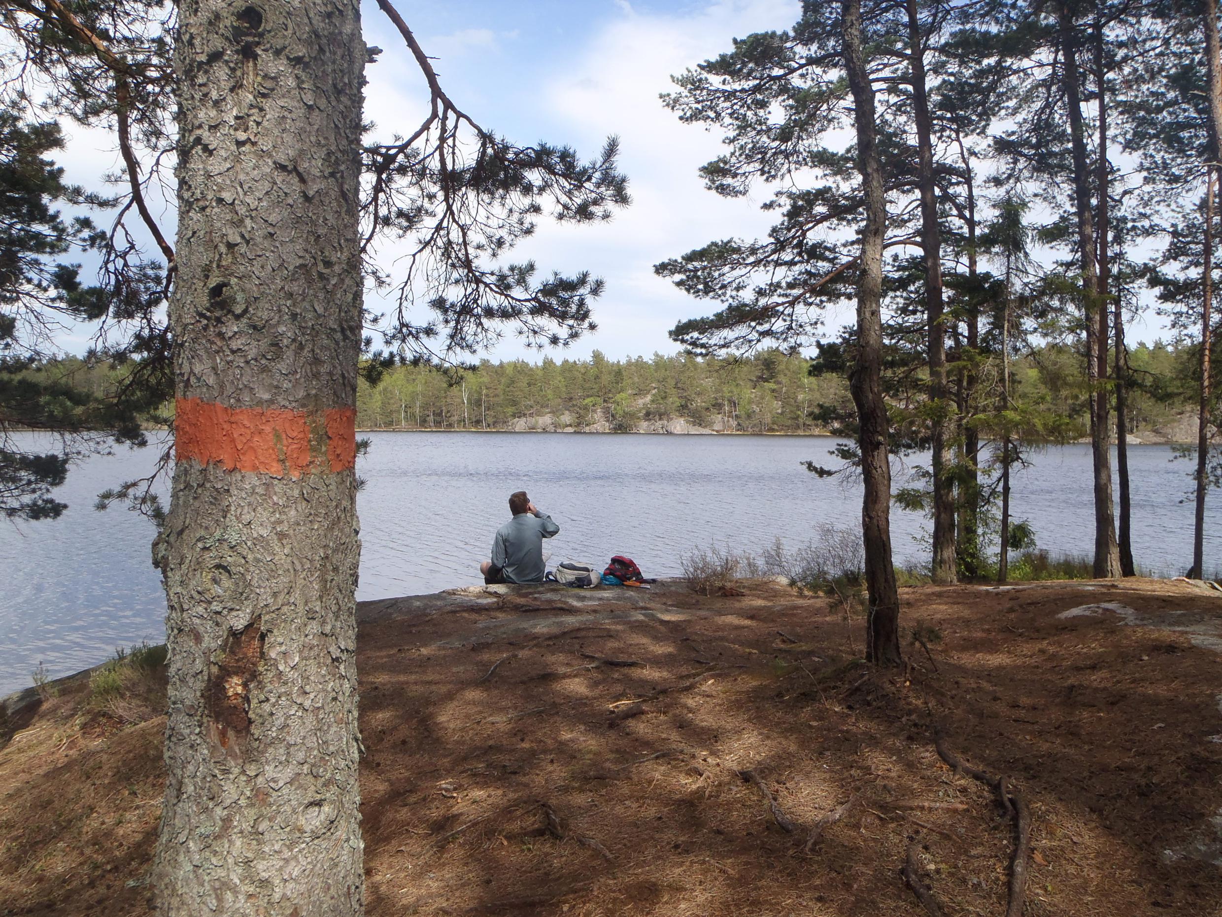 Een man zit aan de oevers van een meer.