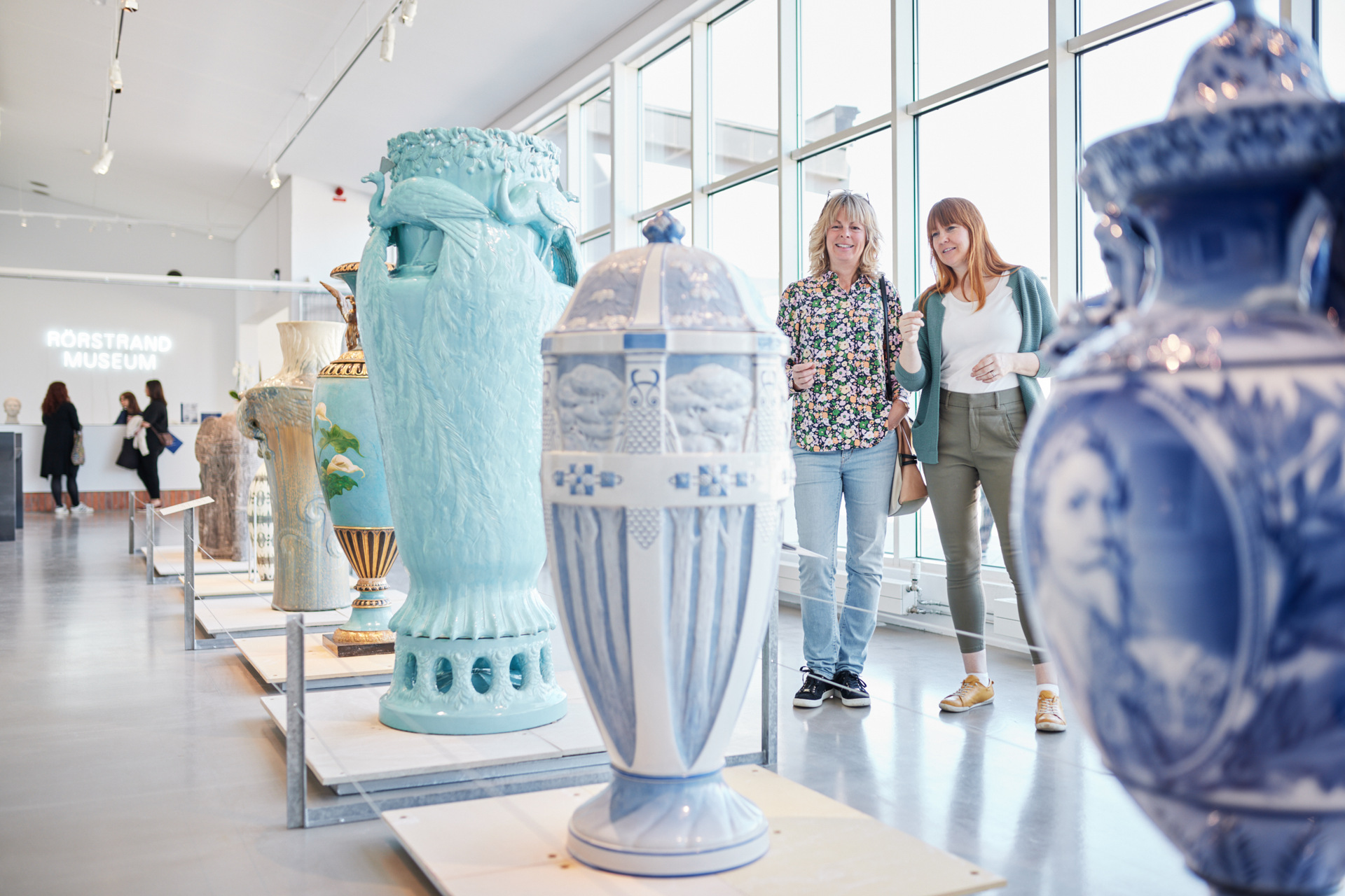 Two visitors viewing large decorative porcelain vases at Rörstrand Museum in Lidköping.