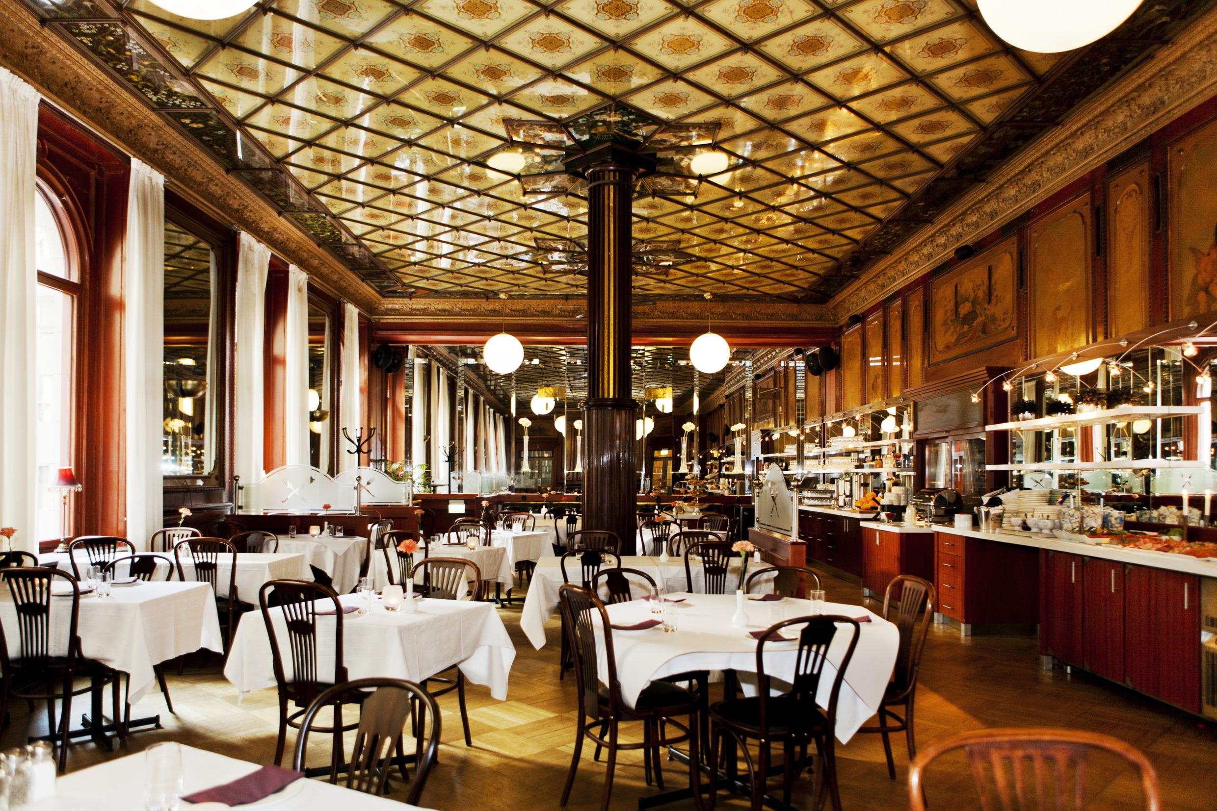 Restaurant met meerdere tafels en spiegels in het plafond.