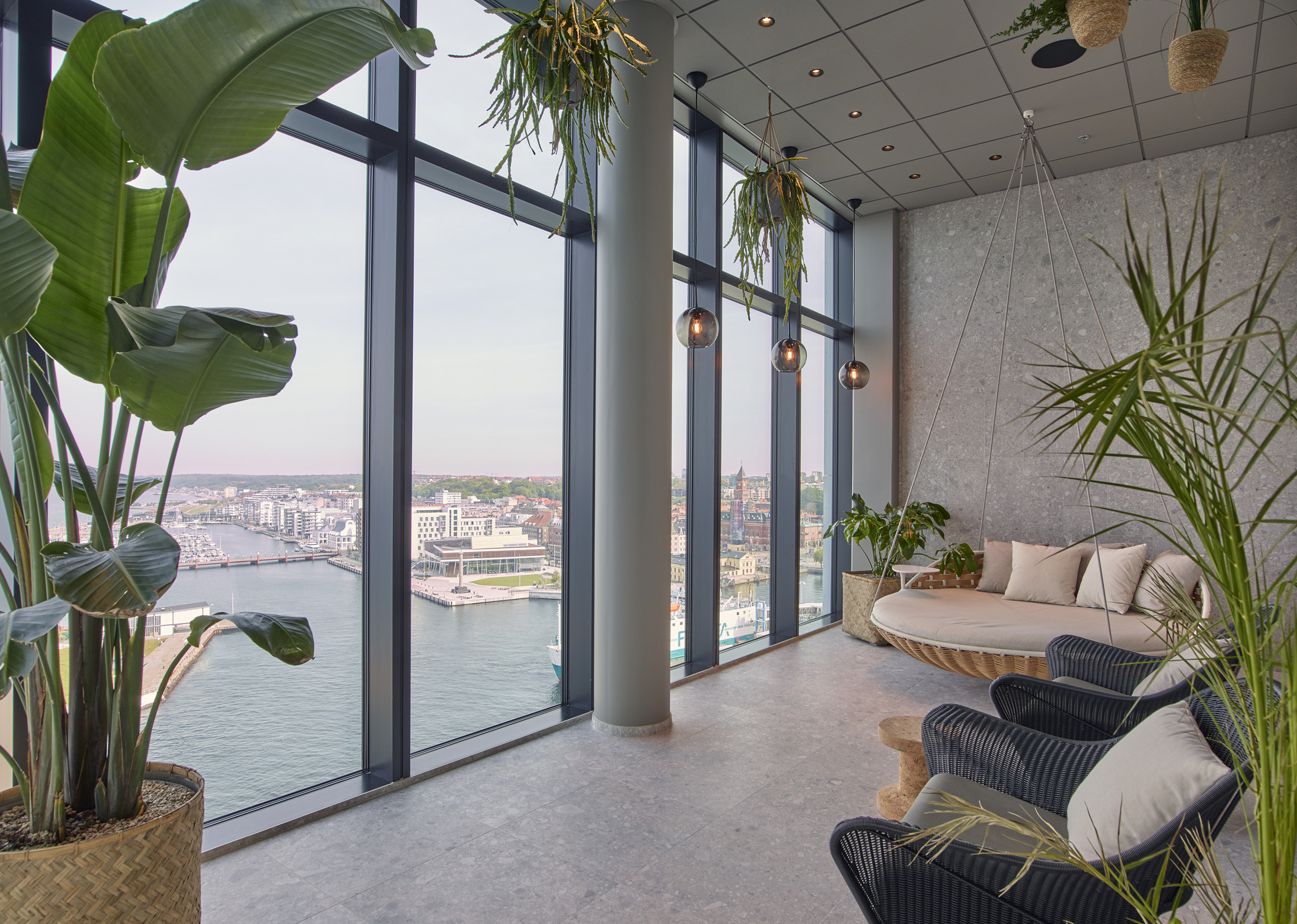 Moderner Lounge-Bereich mit Panoramafenstern mit Blick auf den Hafen und das Stadtbild im Scandic Oceanhamnen Hotel in Helsingborg.