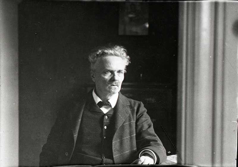 A portrait of August Strindberg looking out of a window in 1908.