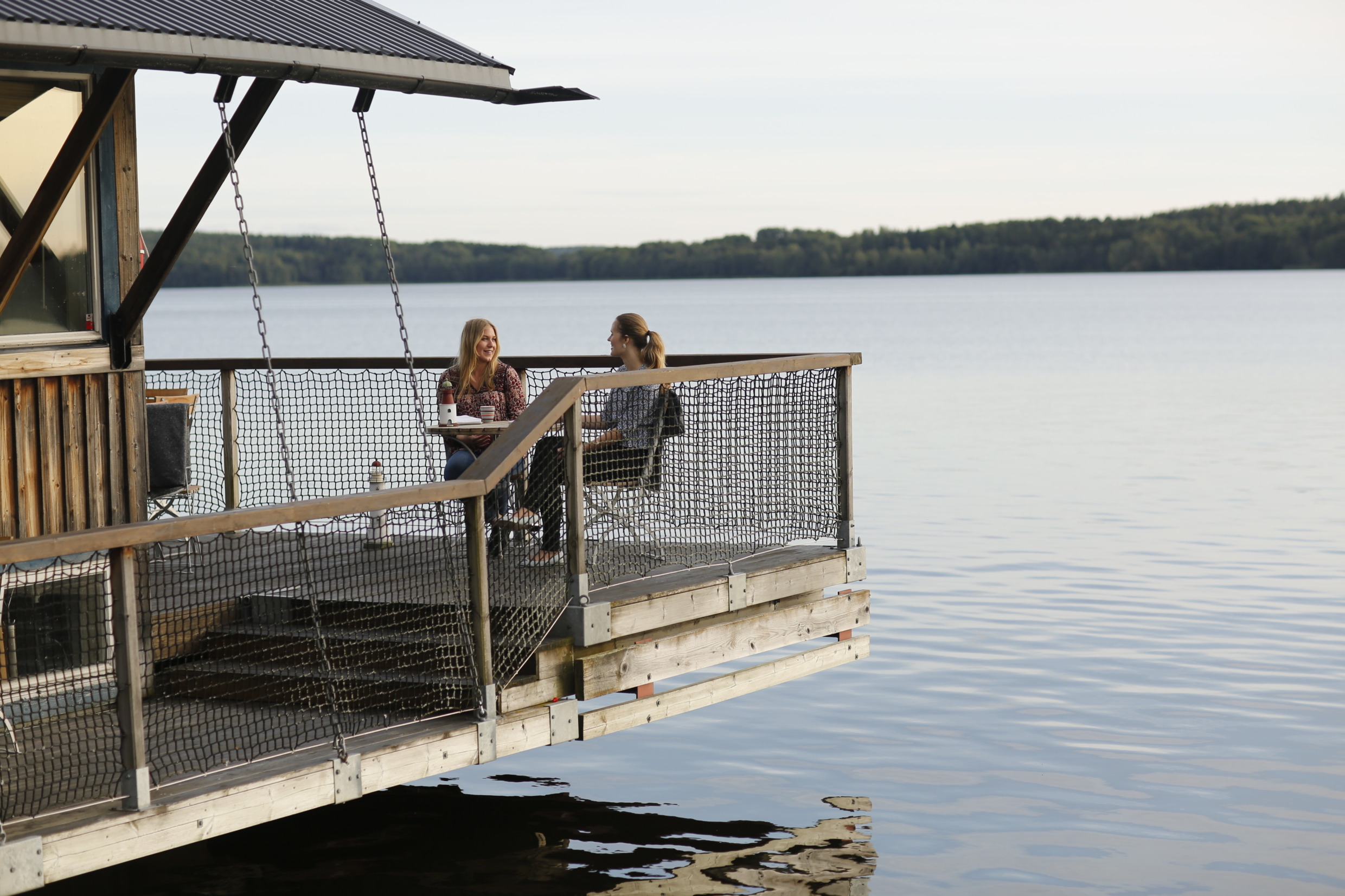 Two women enjoying a meal at Båthuset Krog & Bar in Sigtuna, with a view of Sigtunafjärden in the background