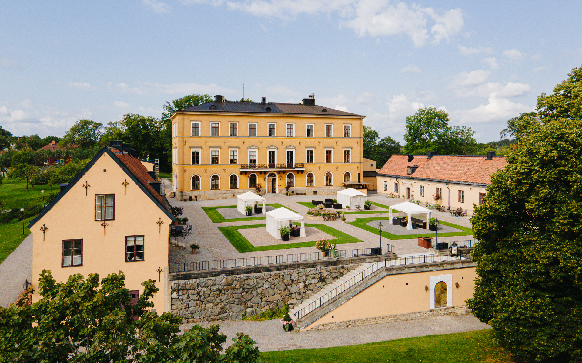 Vue aérienne du château d'Ulfsunda, mettant en avant son manoir historique, sa cour paysagée et ses jardins entourés d'arbres, près de Stockholm.