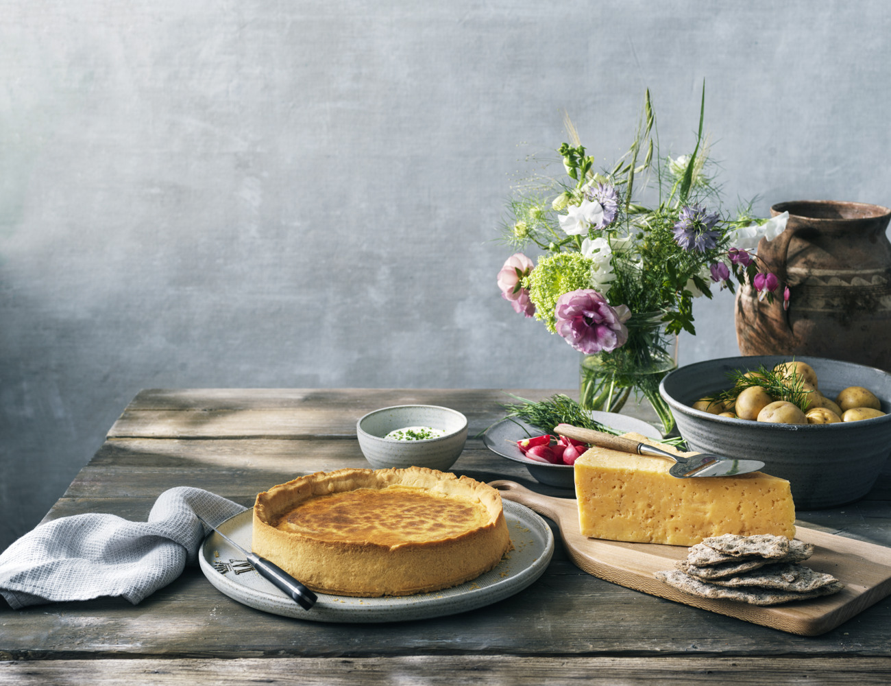 A Västerbotten cheese pie served alongside a wedge of Västerbotten cheese, crispbread and new potatoes.