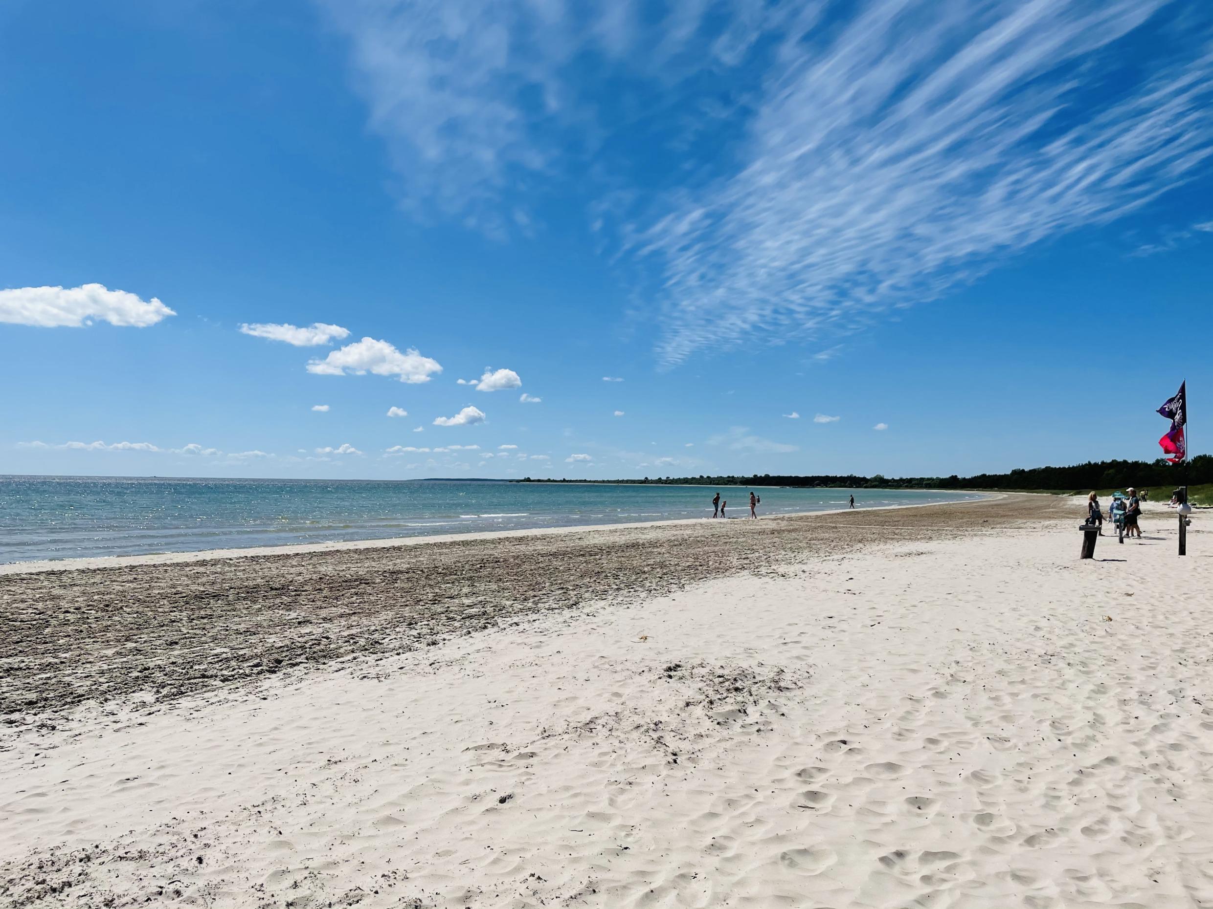 Ein langer, leerer Sandstrand an einem sonnigen Sommertag.