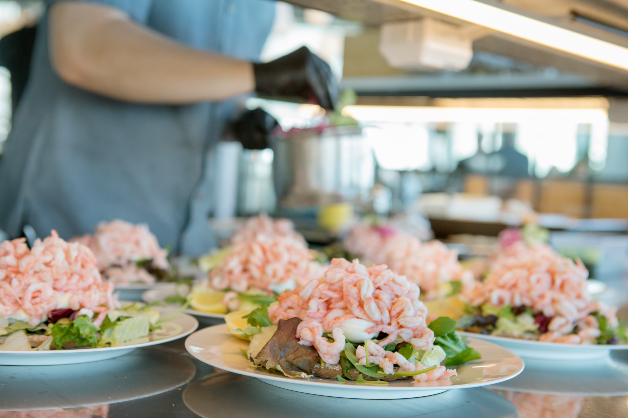 Close-up on a person preparing several king size shrimp sandwich at a restaurant.