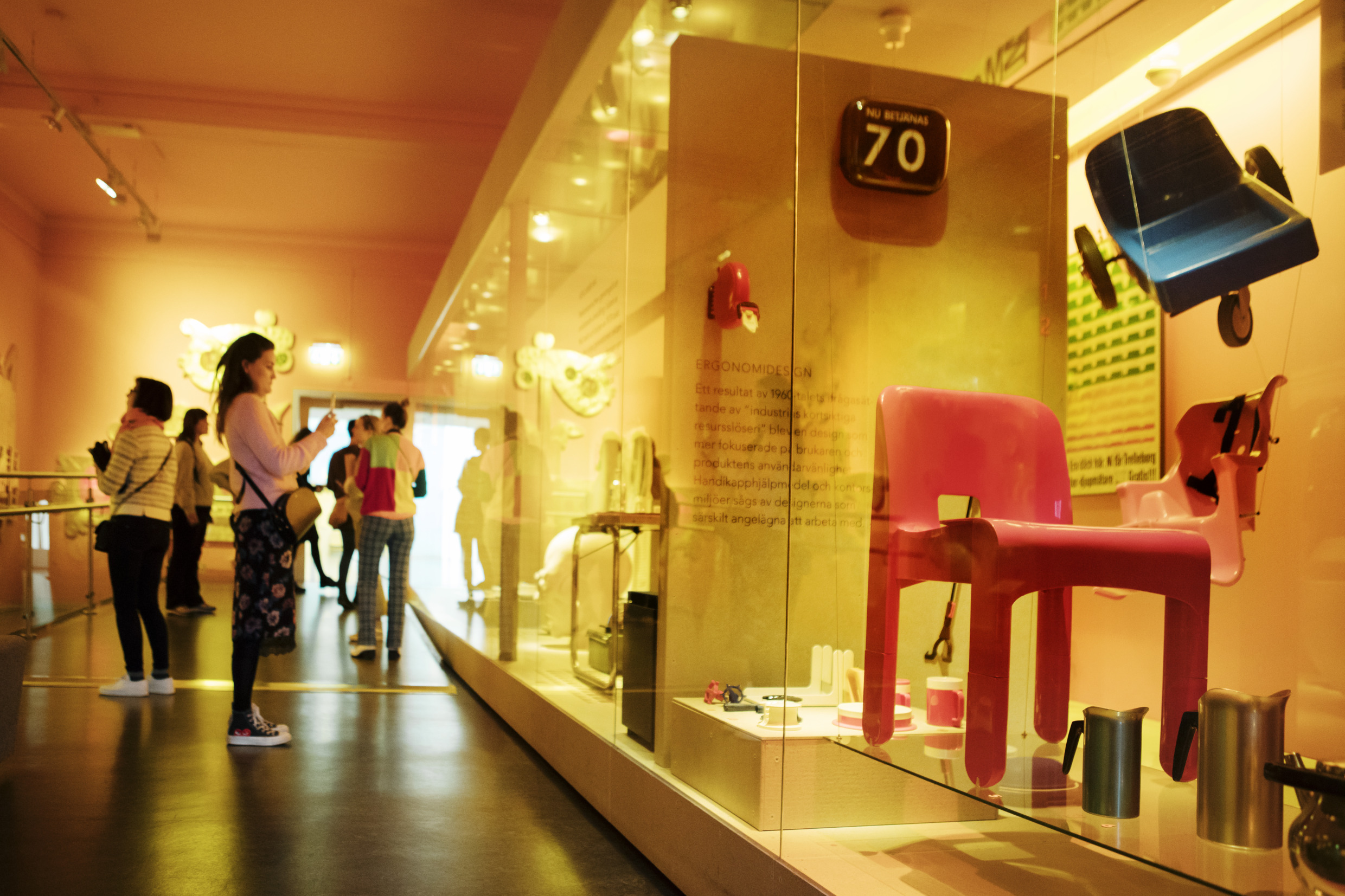 People walking around in an exhibition with design products at a museum.