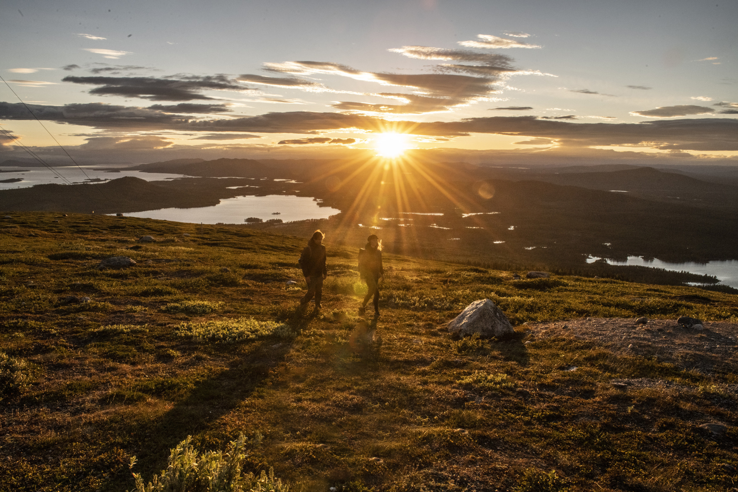 Unter der Mitternachtssonne wandern zwei Menschen durch das arktische Schweden.