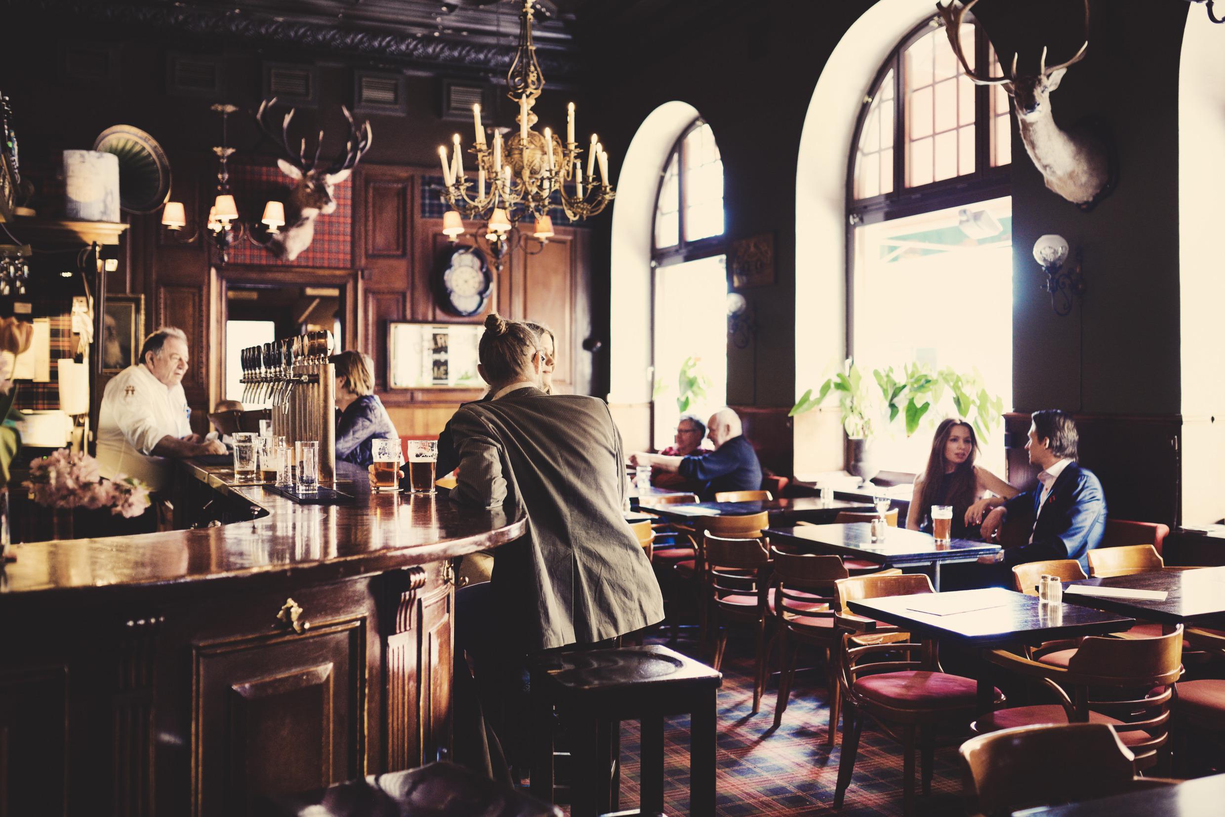Mensen zitten in de bar en aan de tafels in het restaurant Tennstopet.