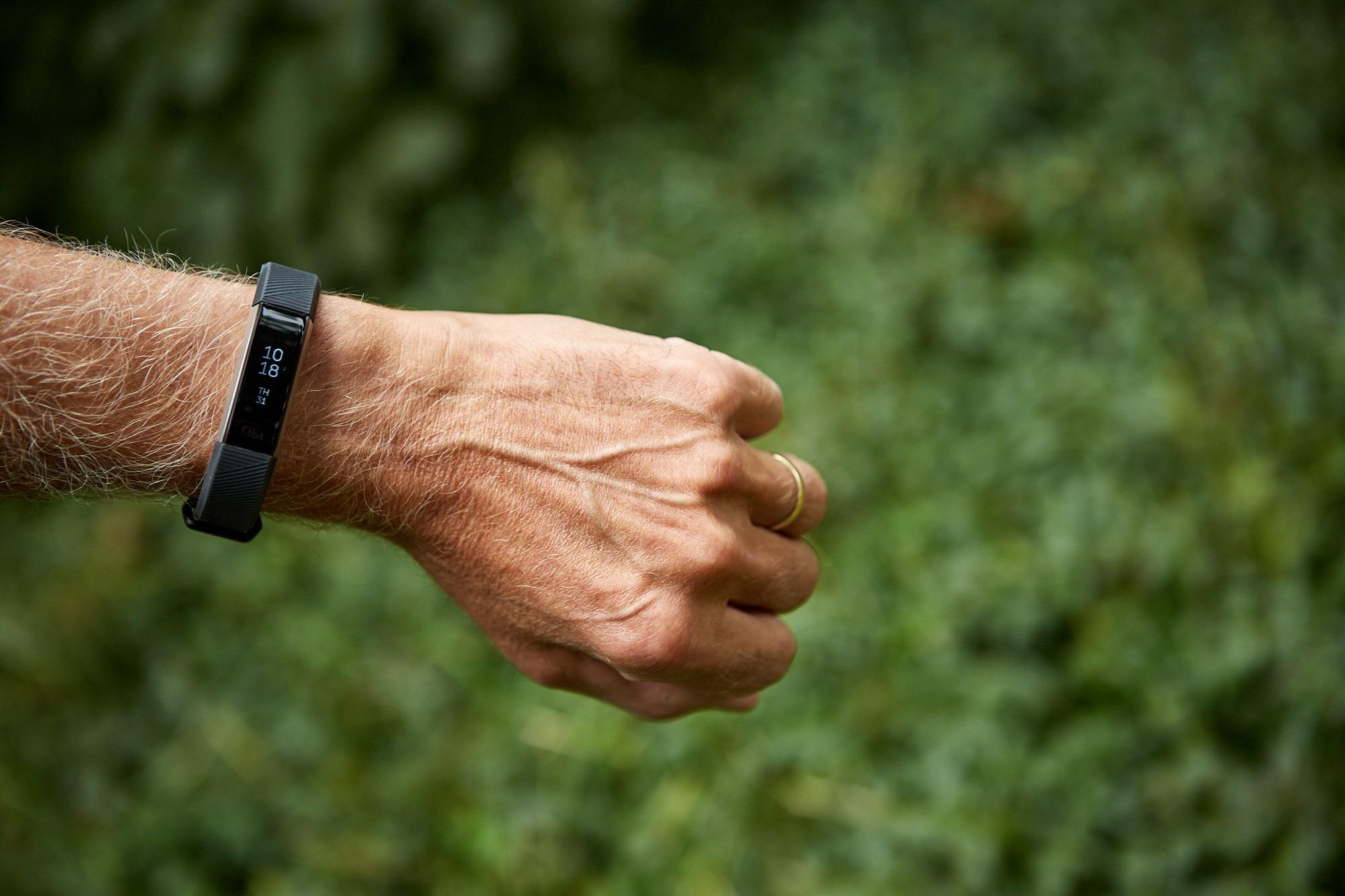 A man holds out a fist, wearing a wristband.