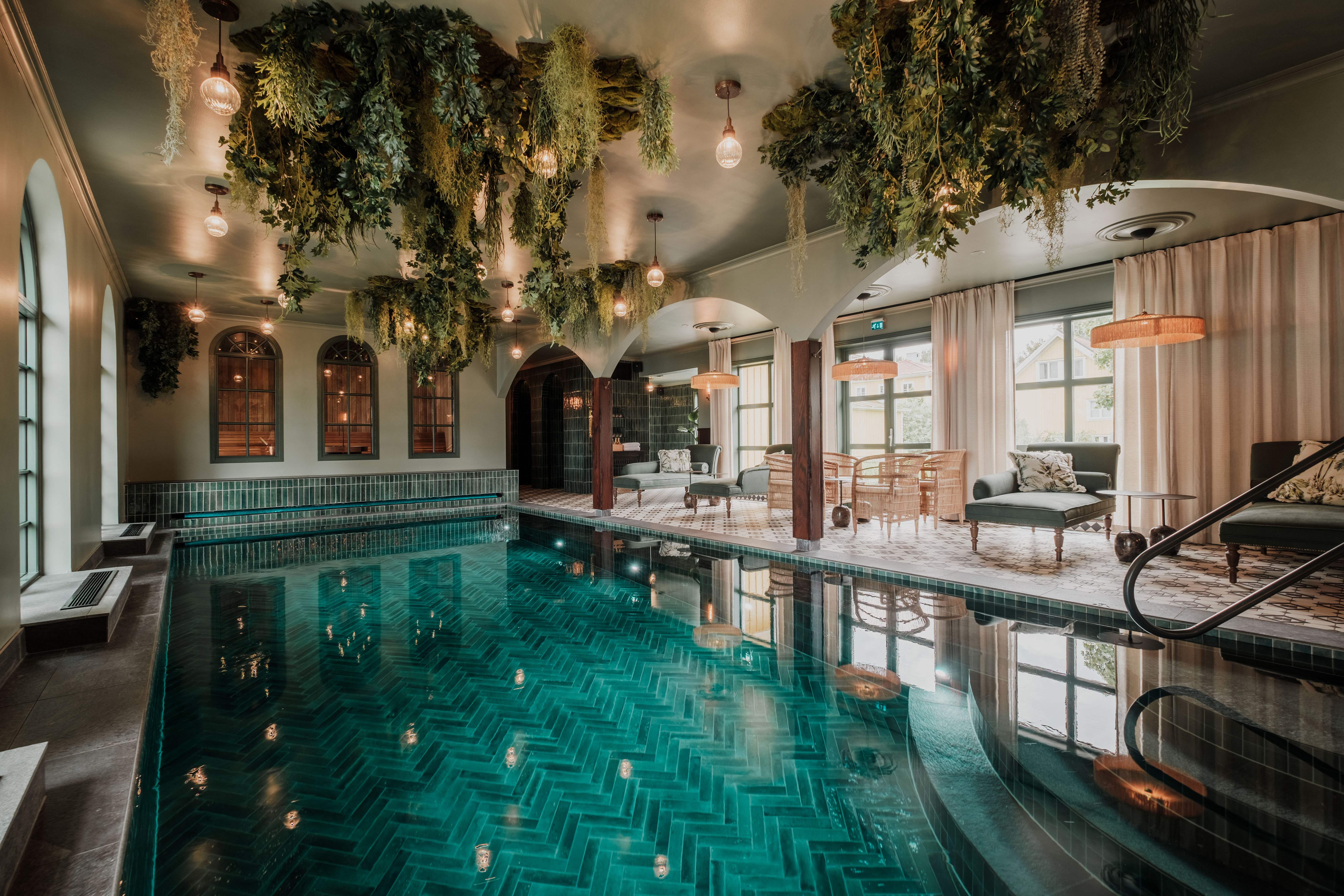 Le spa du château de Lejondal, doté d'une piscine intérieure, d'un coin salon, de plantes suspendues et de grandes baies vitrées donnant sur le parc environnant.