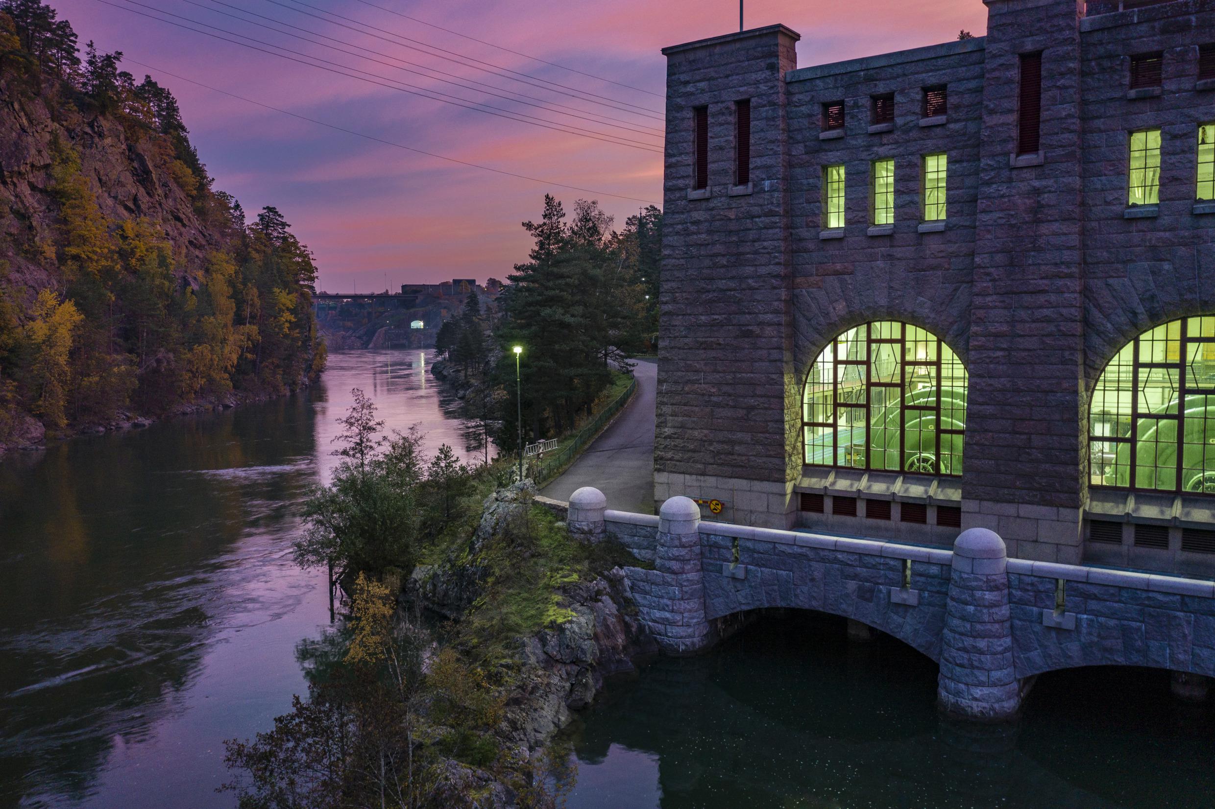 Ein roter Dämmerungshimmel, eine Wasserstraße und ein altes Backsteingebäude mit grünen Lichtern darin.