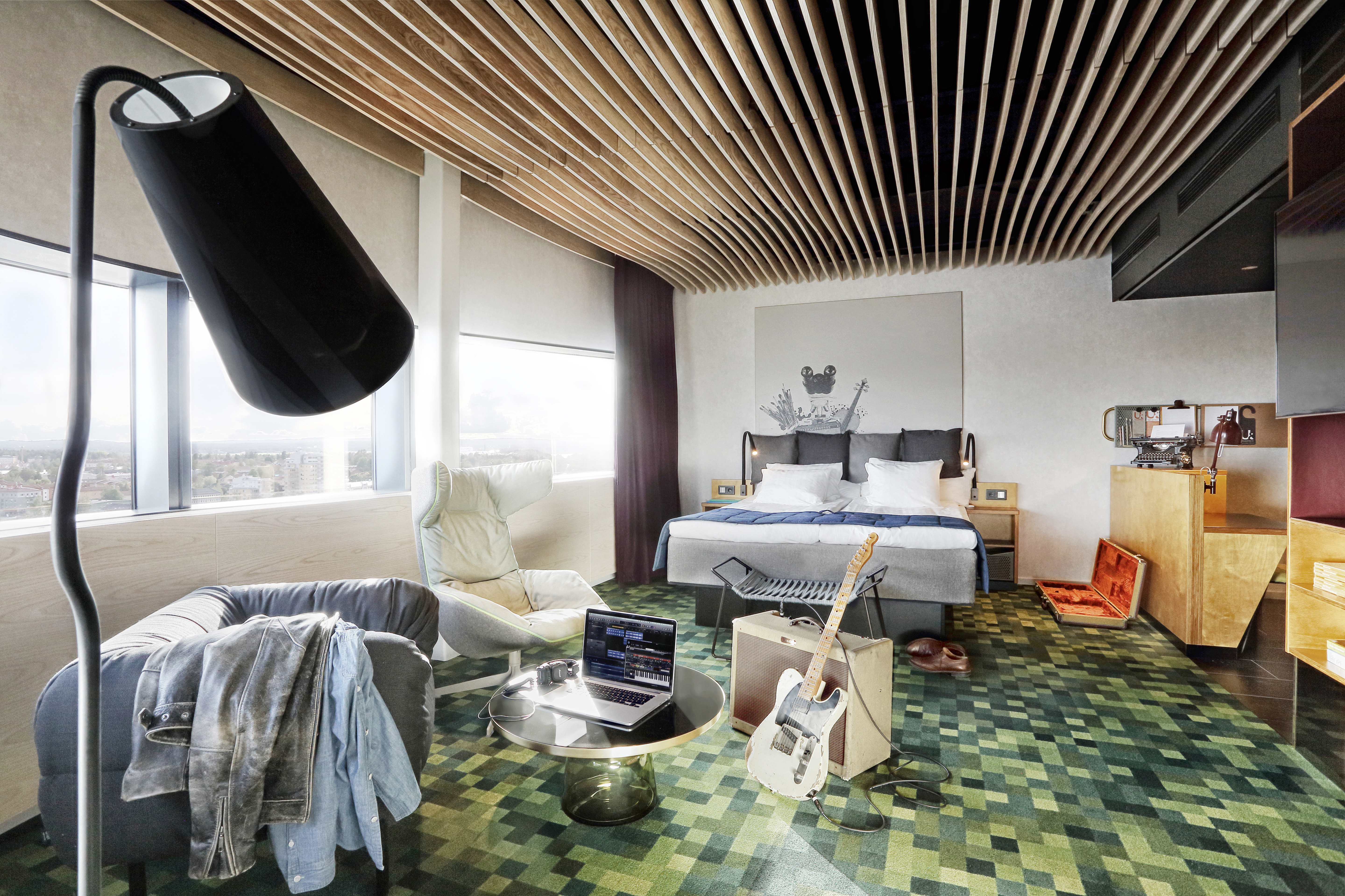A modern guest room at U&Me hotel in Umeå, with contemporary furnishings and large windows overlooking the city.