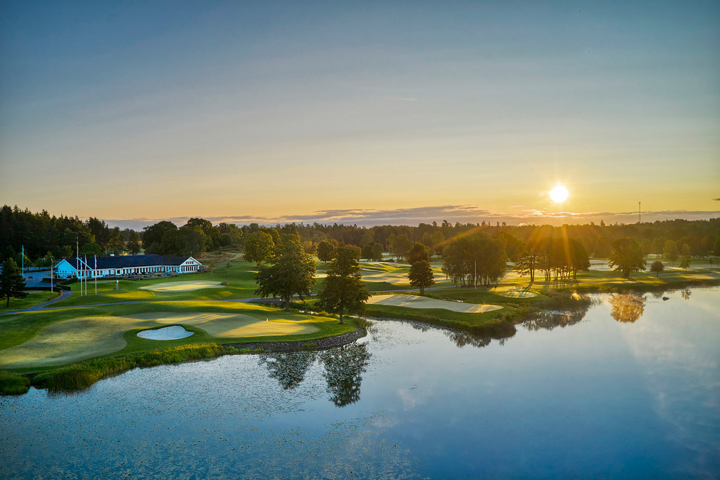 Ullna golf course in sunset with view over lake, bunkers, fairway and clubhouse