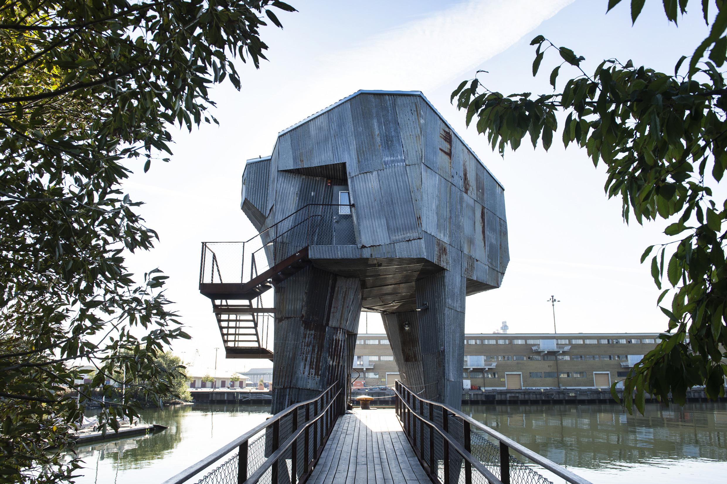 A metallic sauna made from recycled material standing by the sea in a harbour.